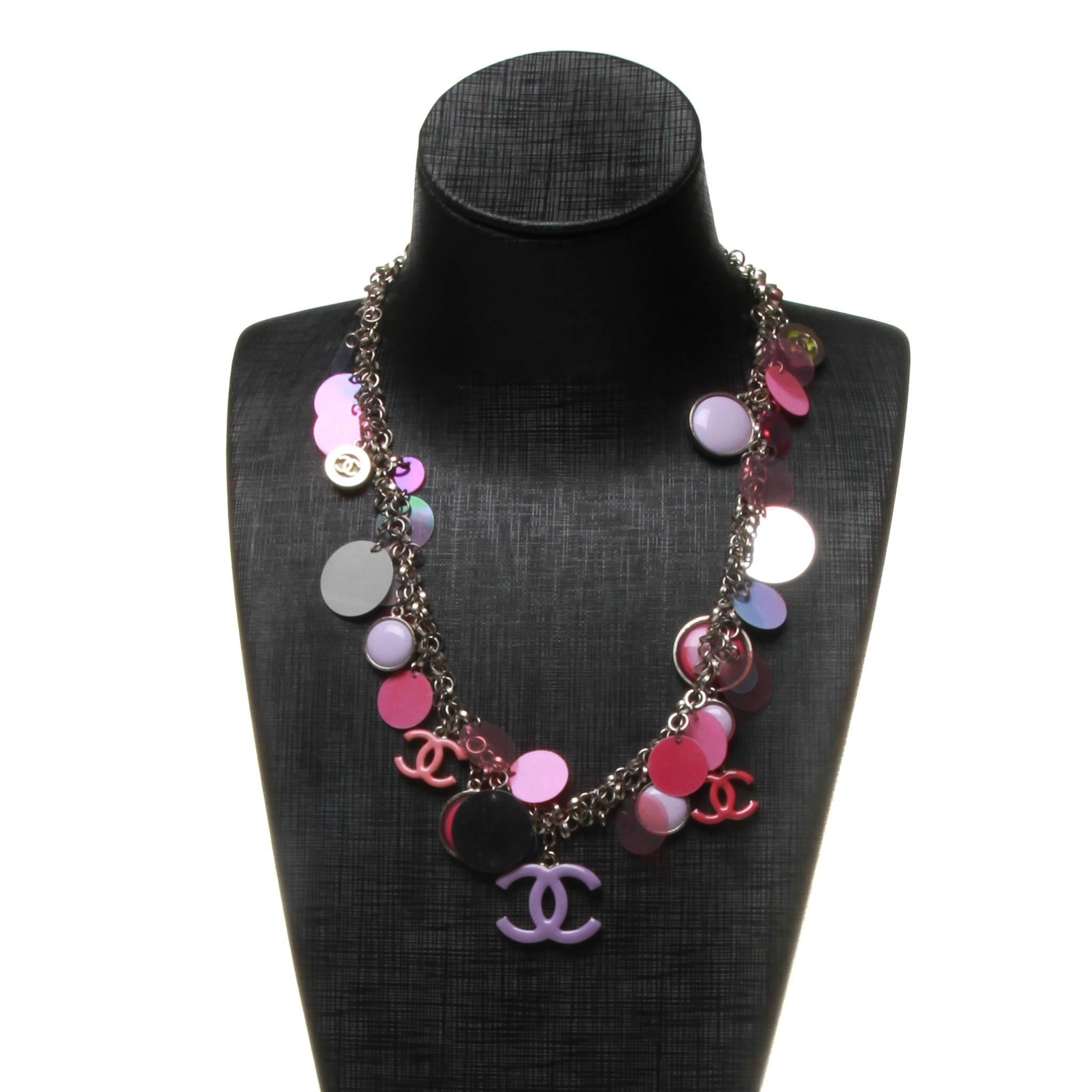 Chanel necklace featuring a motif of purple, pink, grey, green and translucent sequin disks and CC charms on a silver-tone rolo chain with loose silver links running its length. 
Lobster clasp closure at back with CC disk and date stamp 04 P.

