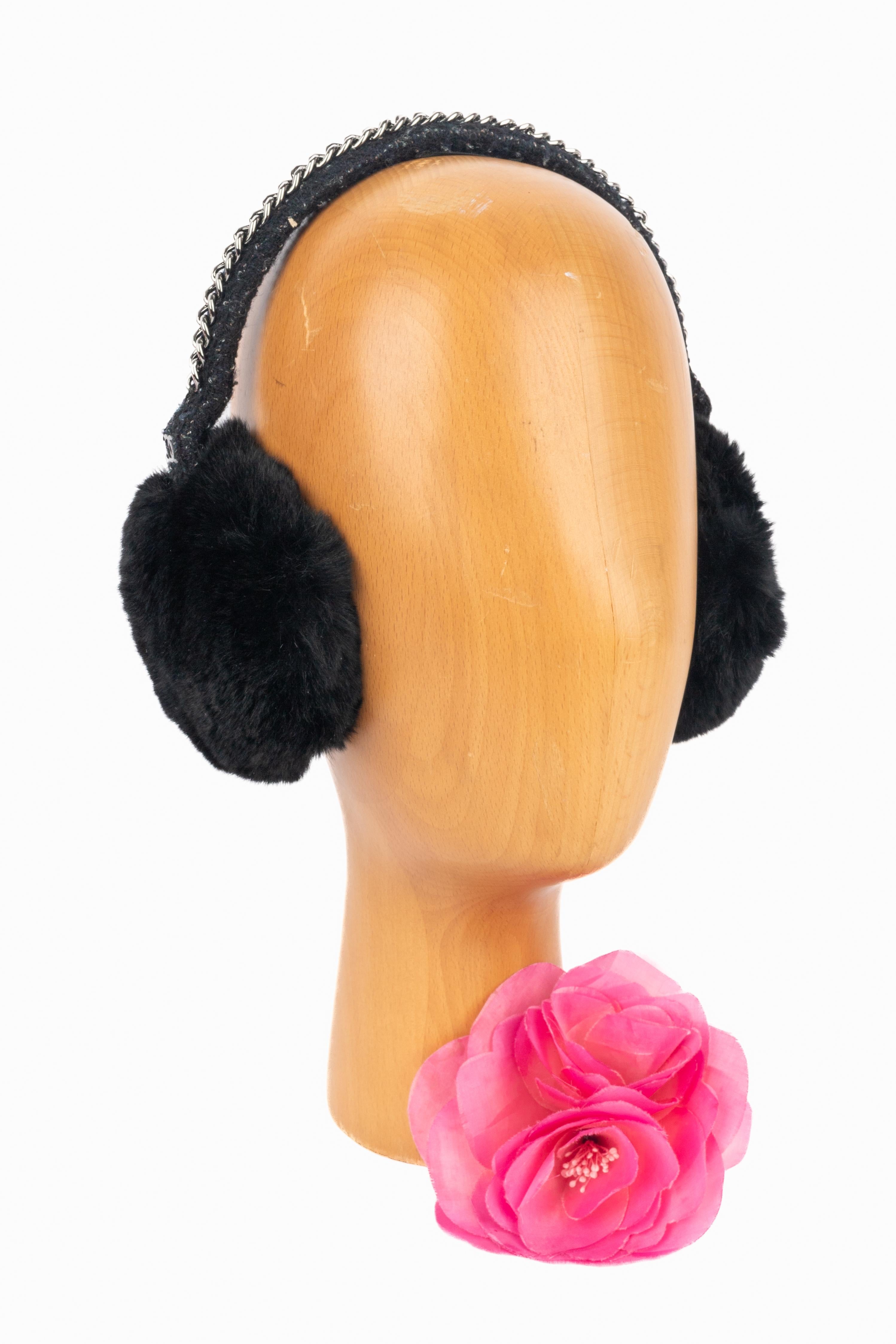 Chanel - Paraorecchie in tweed sormontati da una catena di metallo argentato e da una pelliccia nera. Una collezione del 2000 circa sotto la direzione artistica di Karl Lagerfeld.

Condizioni:
Ottime condizioni

Dimensioni:
Lunghezza: 46