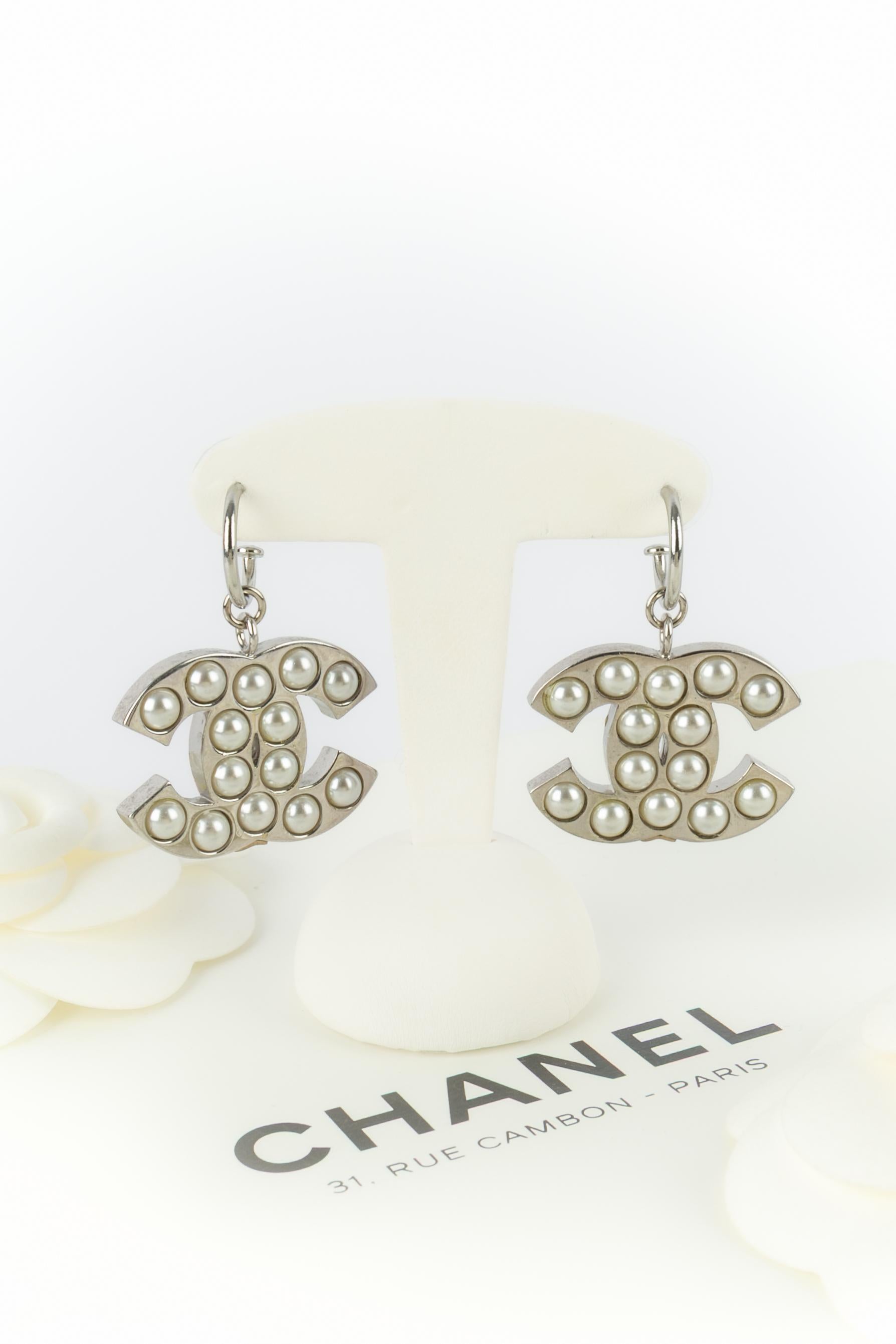 CHANEL - (Fabriqué en France) Boucles d'oreilles cc en métal argenté ornées de cabochons nacrés fantaisie. Collectional automne-hiver 2004 sous la direction artistique de Karl Lagerfeld.

Condit :
Très bon état.

Dimensions :
Longueur : 4