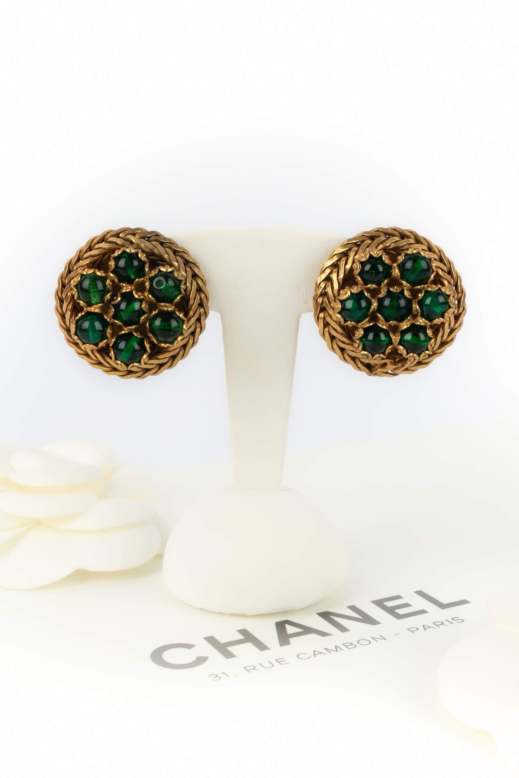 CHANEL - (Made in France) Braided golden metal clip-on earrings centered with emerald-like glass paste pearls. Not signed. Work from the Denez Atelier circa 1970.

Condition:
Very good condition

Dimensions:
Diameter: 2.5 cm

SKU:BOB295