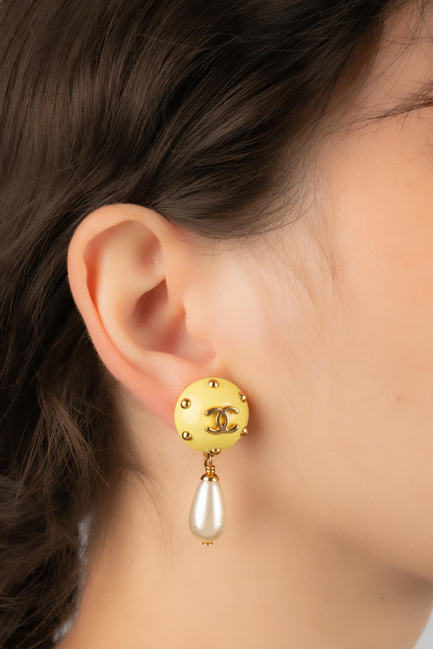 CHANEL - (Made in France) Golden metal clip-on earrings with yellow bakelite and costume pearly drops. 1996 Cruise Collection under the artistic direction of Karl Lagerfeld.

Condition:
Very good condition

Dimensions:
Length: 4 cm

SKU:BOB65