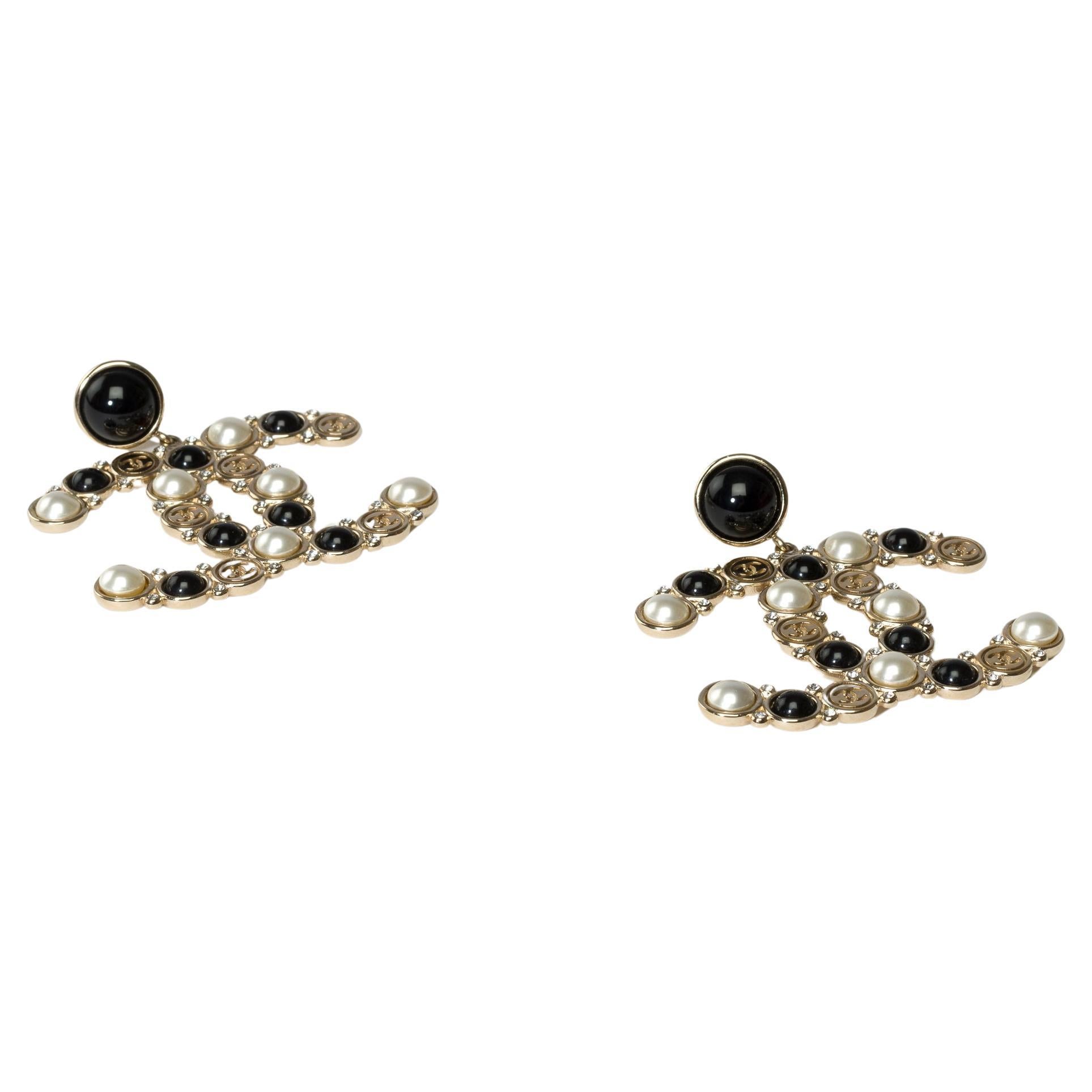 Superbes boucles d'oreilles Chanel CC en métal argenté surmontées de fausses perles, de strass et de résine.

Marque : Chanel
Tags : Boucles d'oreilles pour hommes 
Matière : Métal argenté, fausses perles, strass et résine
Dimensions : 5x4 cm (2x1,6