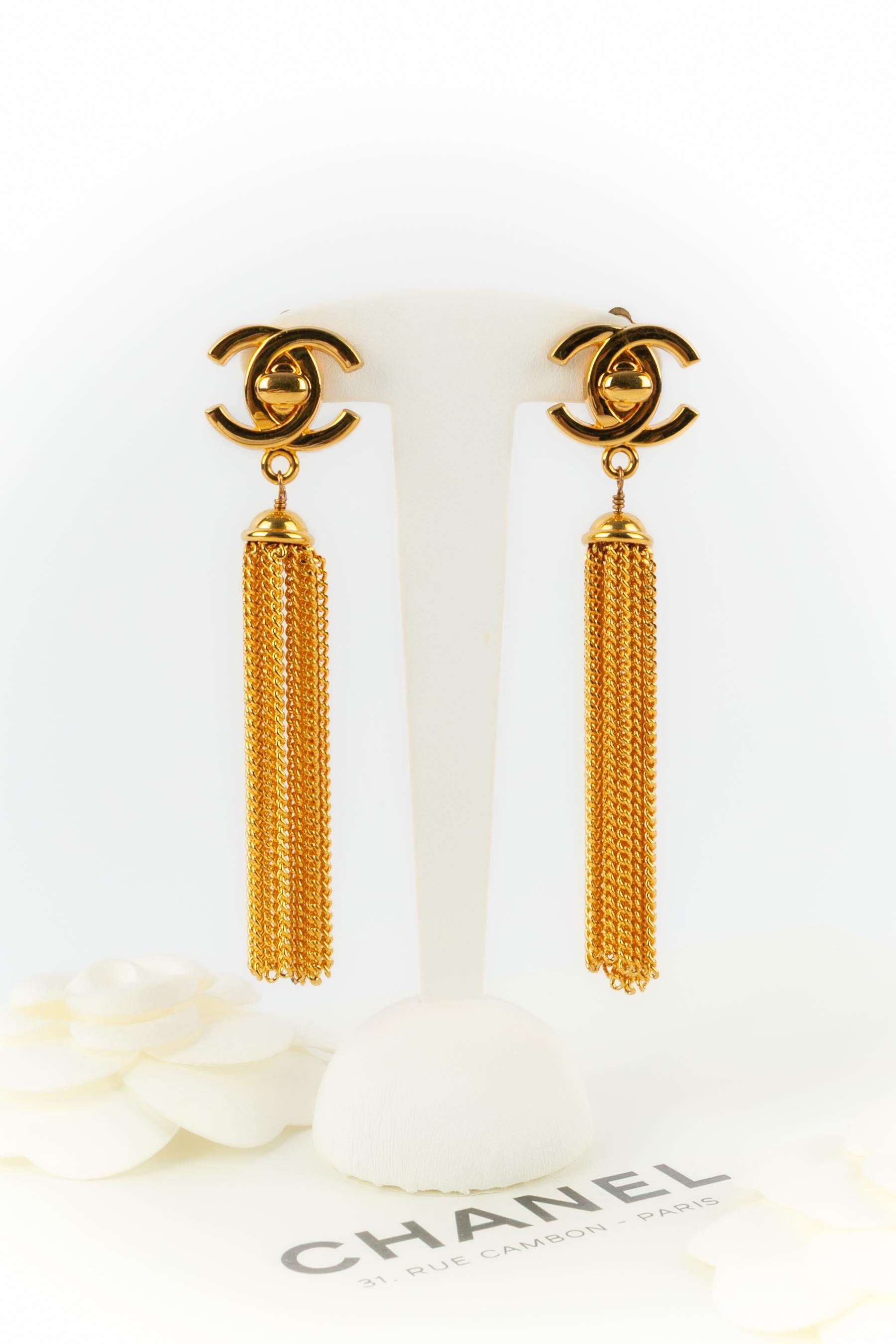 CHANEL - (Made in France) Pendientes de cierre giratorio de metal dorado con pompón de cadena de metal dorado. Colección Otoño-Invierno 1996 bajo la dirección artística de Karl Lagerfeld.

Estado:
Muy buen estado

Dimensiones:
Longitud: 9.5
