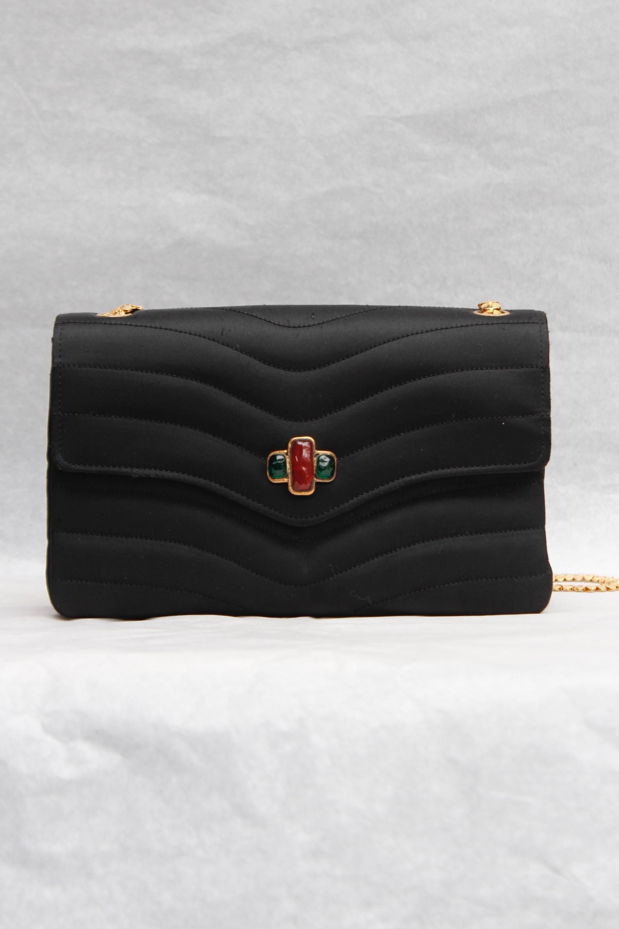 CHANEL (Made in France) Elegant evening bag in black satin over stitched with waves pattern. The flap is decorated with a a gilded metal and ruby and emerald glass paste element. It can be worn over the shoulder or cross-body, thanks to a lovely