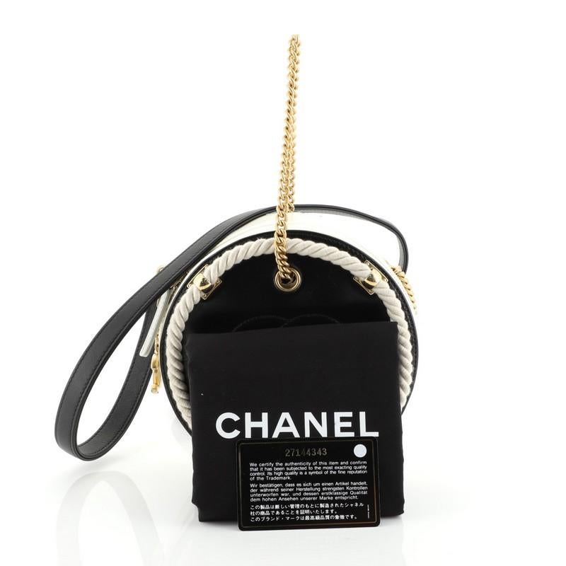 This Chanel En Vogue Round Bag Crumpled Calfskin Small, crafted in white and black leather, features chain-link strap with leather pad, twisted rope trims with gold detailing and gold-tone hardware accents. Its zip closure opens to a blue denim