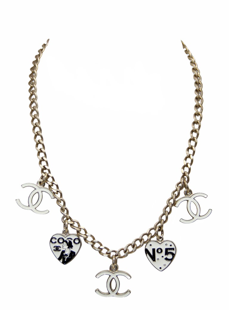 This pre-owned collector item from the house of Chanel is part of the 2006 Spring / Summer collection. 
It is crafted from gold-tone metal. The chain holds 2x Heart shape dangling pendants (1x with Coco CC Logo engraved Mademoiselle and 1x with