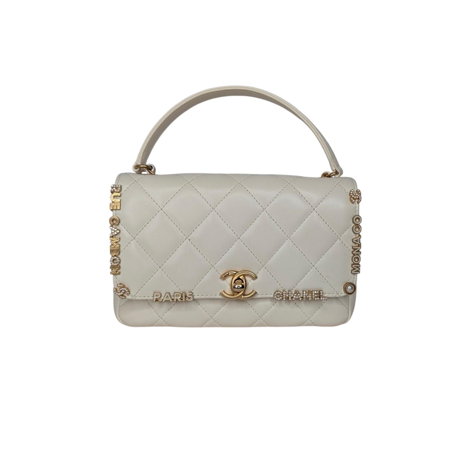 Chanel Cruise 2023 Seasonal Bag Collection by Virginie Viard. This stylish classic flap is finely crafted of white diamond quilted lambskin leather adorned with exquisitely detailed iconic Chanel logos inlaid in enamel and crystals. The bag features