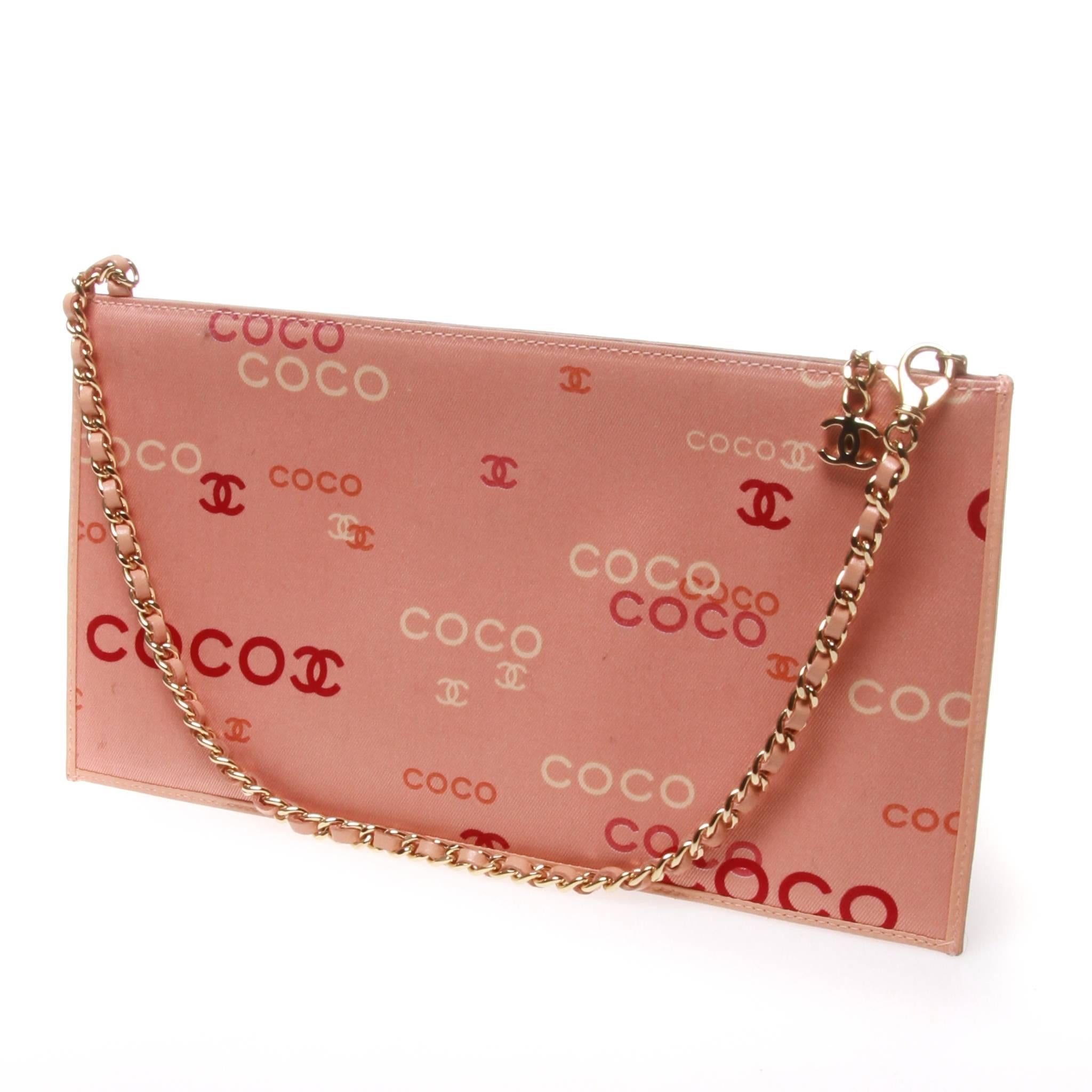 Chanel envelope pouch with coco graphic. The baby pink flat pouch features a pale lining and lambskin detailing. Gold tone classic Chanel chain woven with matching leather. A lobster claw clip to one end of the chain allows the bag to be worn as a