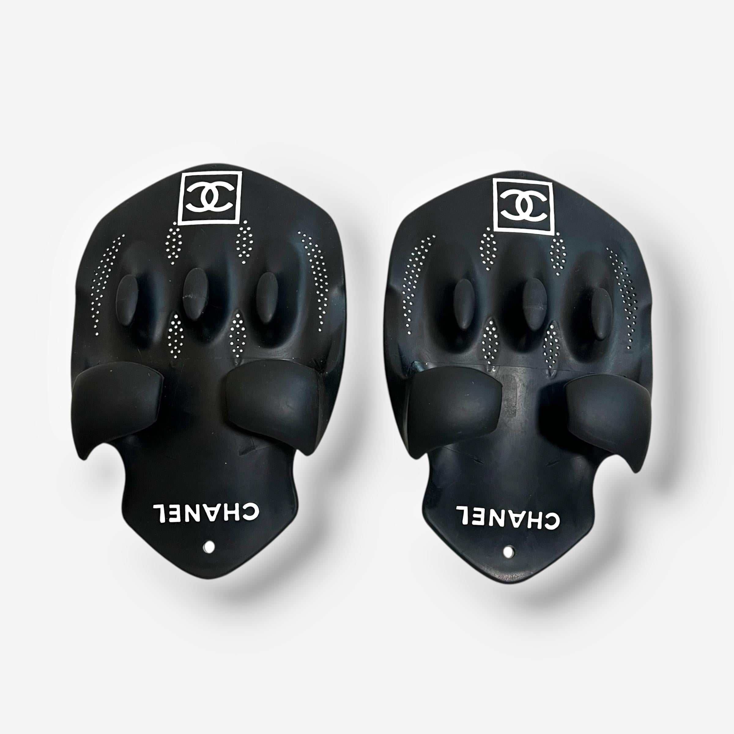 
Par extremadamente raro y coleccionable de aletas ergonómicas para manos de nadador de Chanel, de la década de 1990. Diseñadas para un rendimiento aerodinámico en el agua, estas palas de goma en blanco y negro presentan contornos esculturales y una