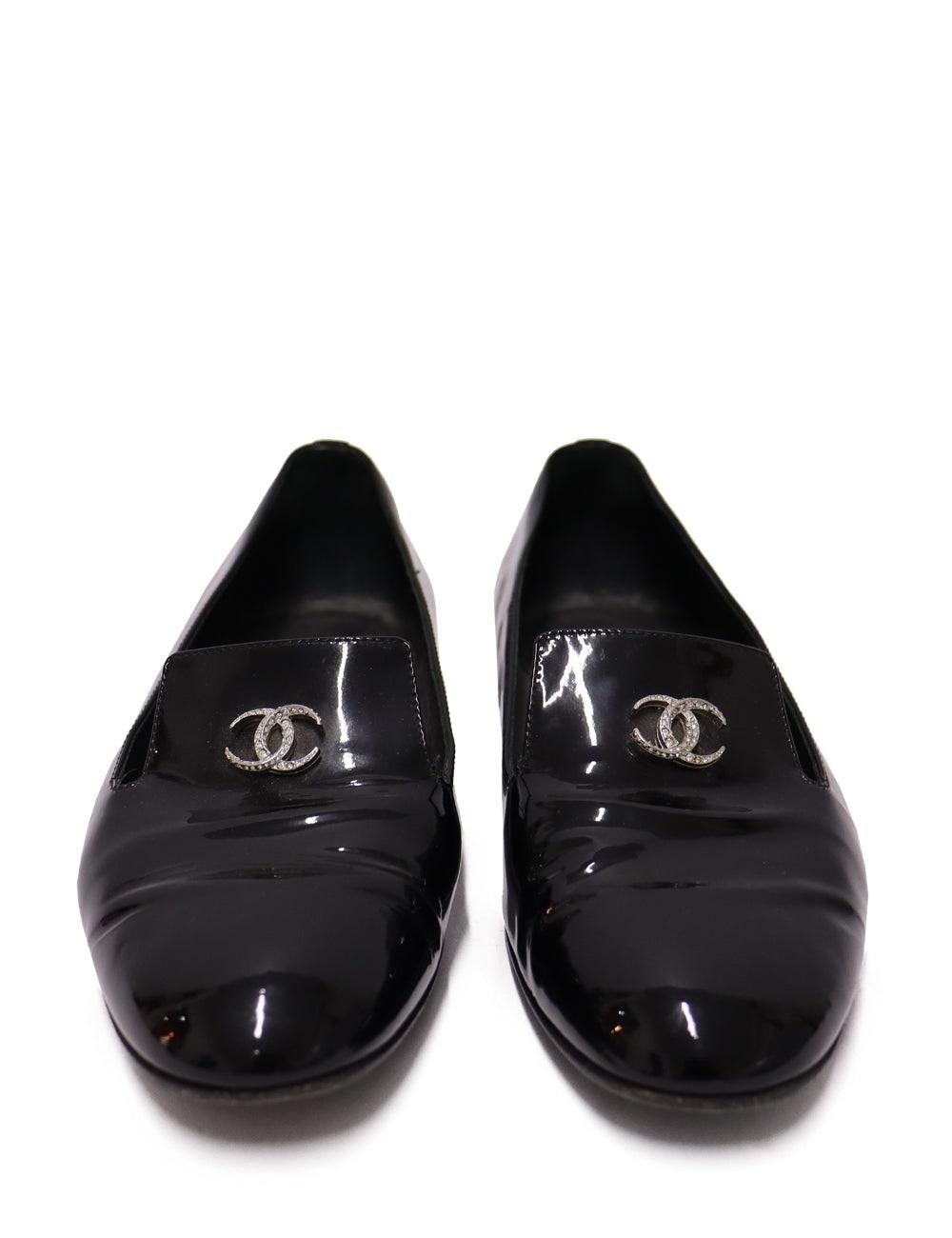 Chanel Black Patent Leather Loafers with a CC Front Crystal Logo.

Additional information:
Material: Leather
Size: EU 37
Measurments: Heel: 1 cm 
Overall Condition: Very Good
Interior Condition: Signs of use
Exterior Condition: Light stains on the