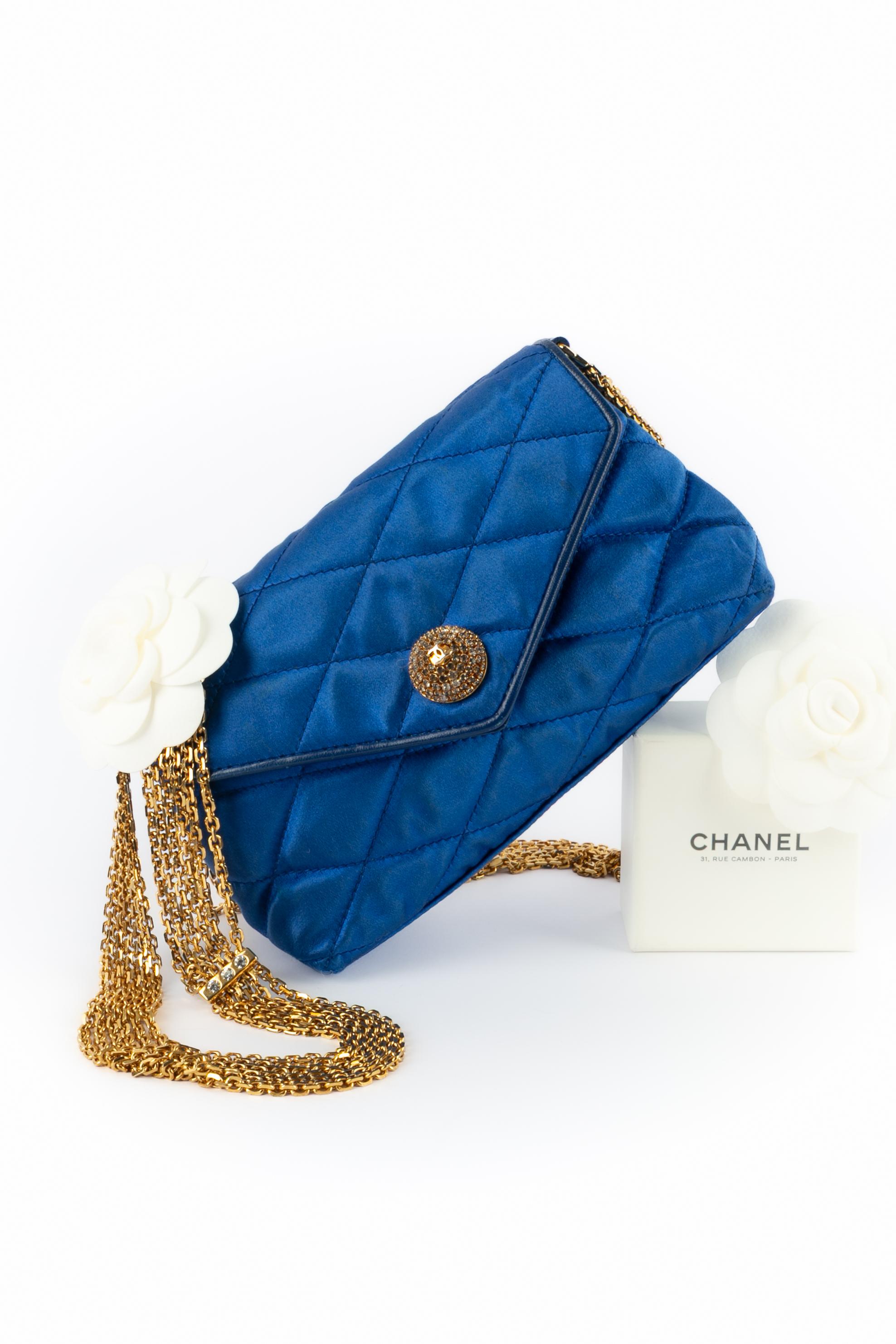 CHANEL - (Made in Italy) Bolso de noche acolchado de satén azul con cierre de presión de metal dorado engastado con brillantes. Asa de cadena de varias filas entrelazadas con brillantes. Pieza con número de serie. Una Colección circa