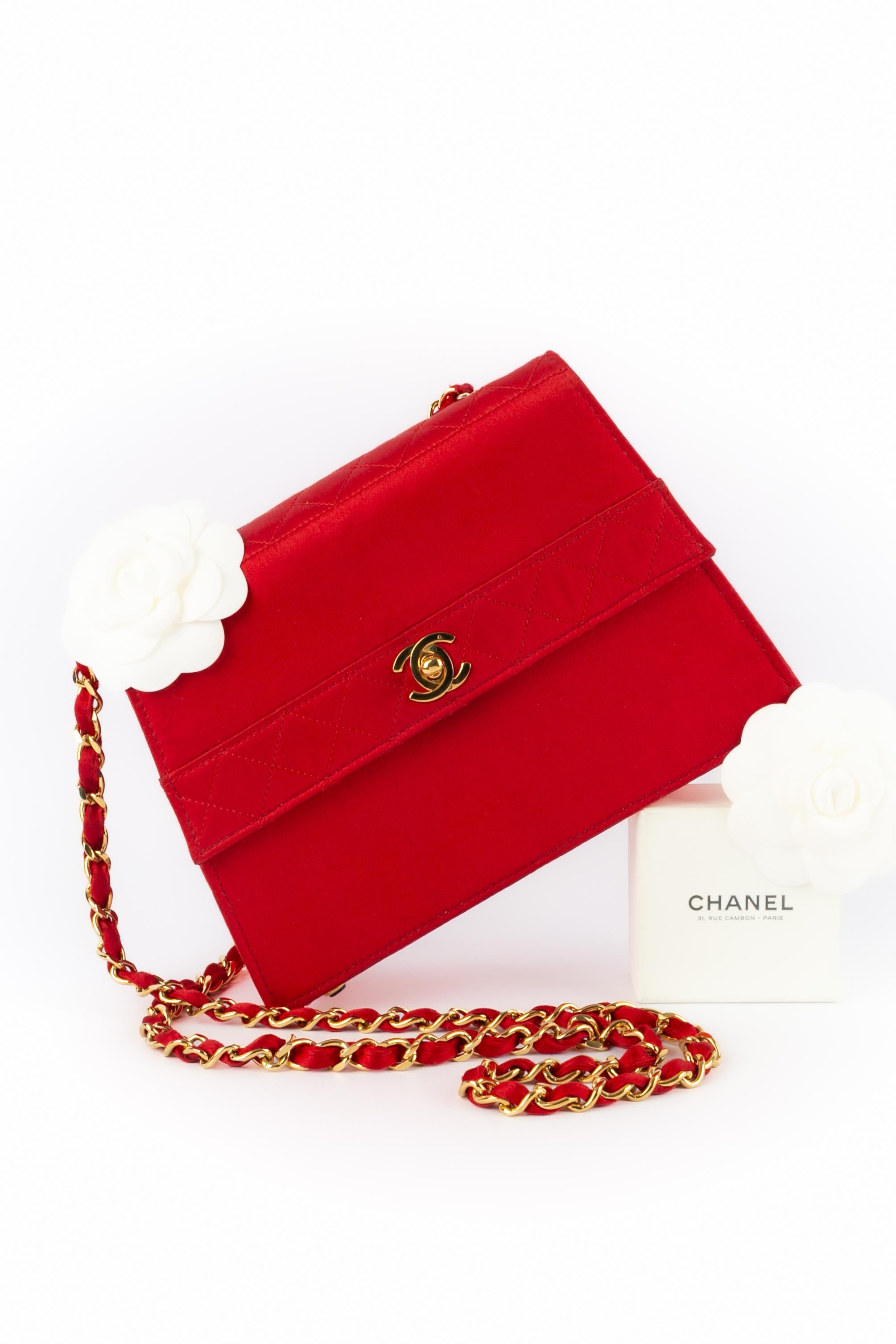 CHANEL - Bolso de noche de satén rojo parcialmente acolchado. Cierre cc de metal dorado, y asa de cadena cruzada de satén entrelazado. Pieza con número de serie. Colección 1989/1991.

Estado:
Muy buen estado

Dimensiones:
Longitud: 18 cm - Altura: