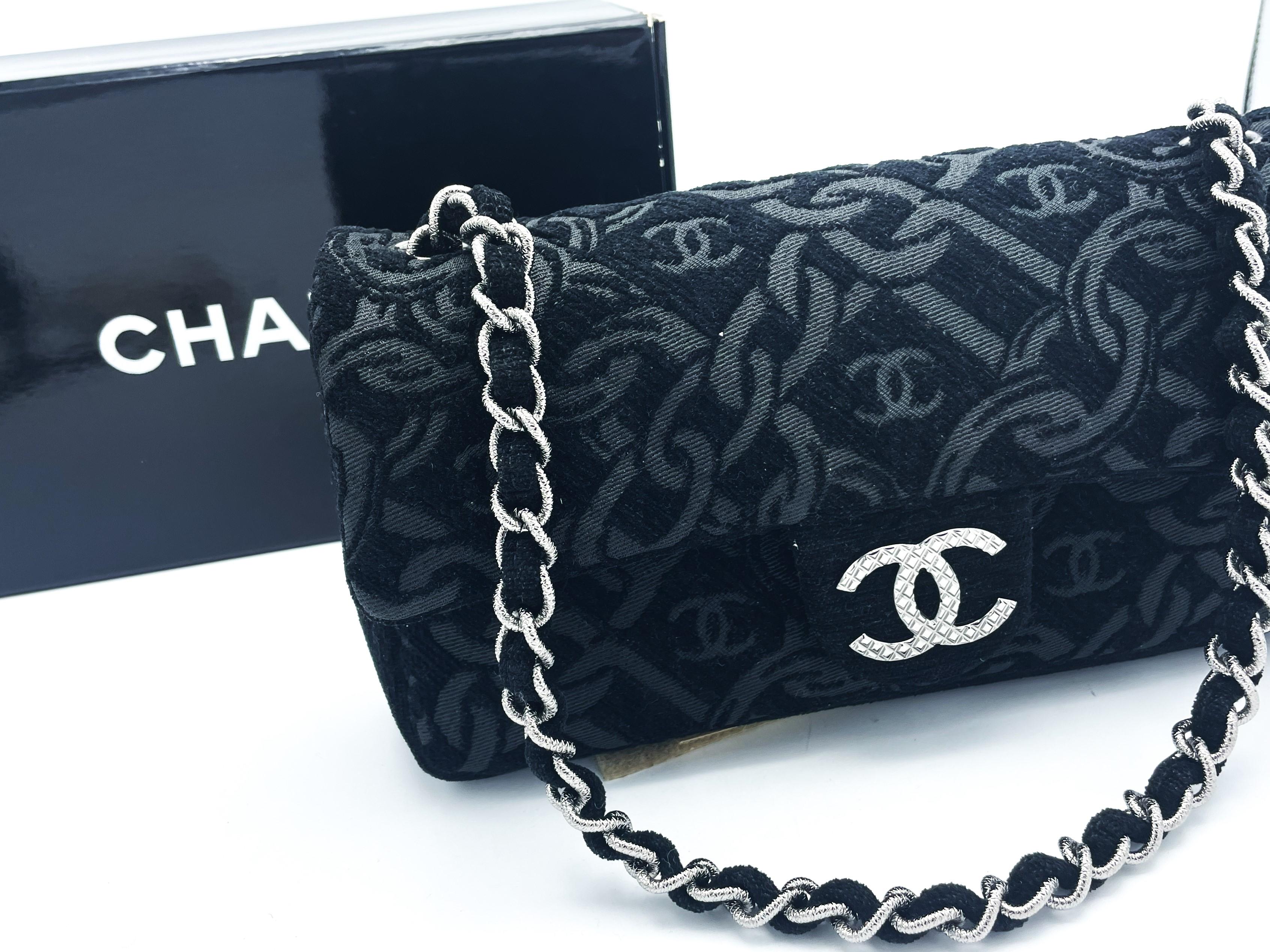 Eine sehr schöne und seltene CHANEL Tasche (Made in Italy)  aus schwarzem Jacquardstoff mit eingewobenem CC Logo und der typischen CHANEL Kette. Silbener CC Verschluss und passende kurze silberne Tragekette. 

Größe:
Breite 24 cm x Höhe 13 cm x