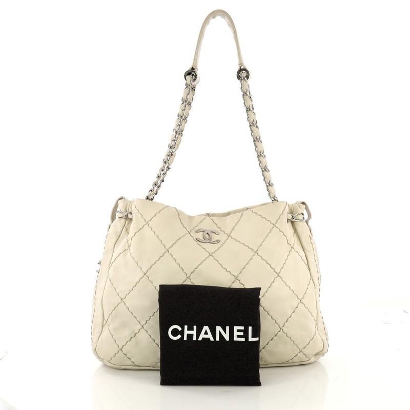 This Chanel Expandable Zip Around Tote Quilted Leather Large, crafted in beige quilted leather, features an iconic CC logo on the front, zip around details for expansion with Chanel CC charm pull, woven-in leather chain straps with padded shoulder