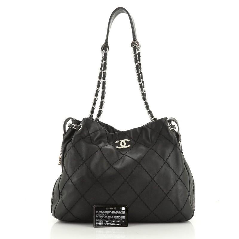 This Chanel Expandable Zip Around Tote Quilted Leather Large, crafted in black quilted leather, features CC logo on the front, zip around details for expansion, woven-in leather chain straps with shoulder pad, and silver-tone hardware. Its magnetic