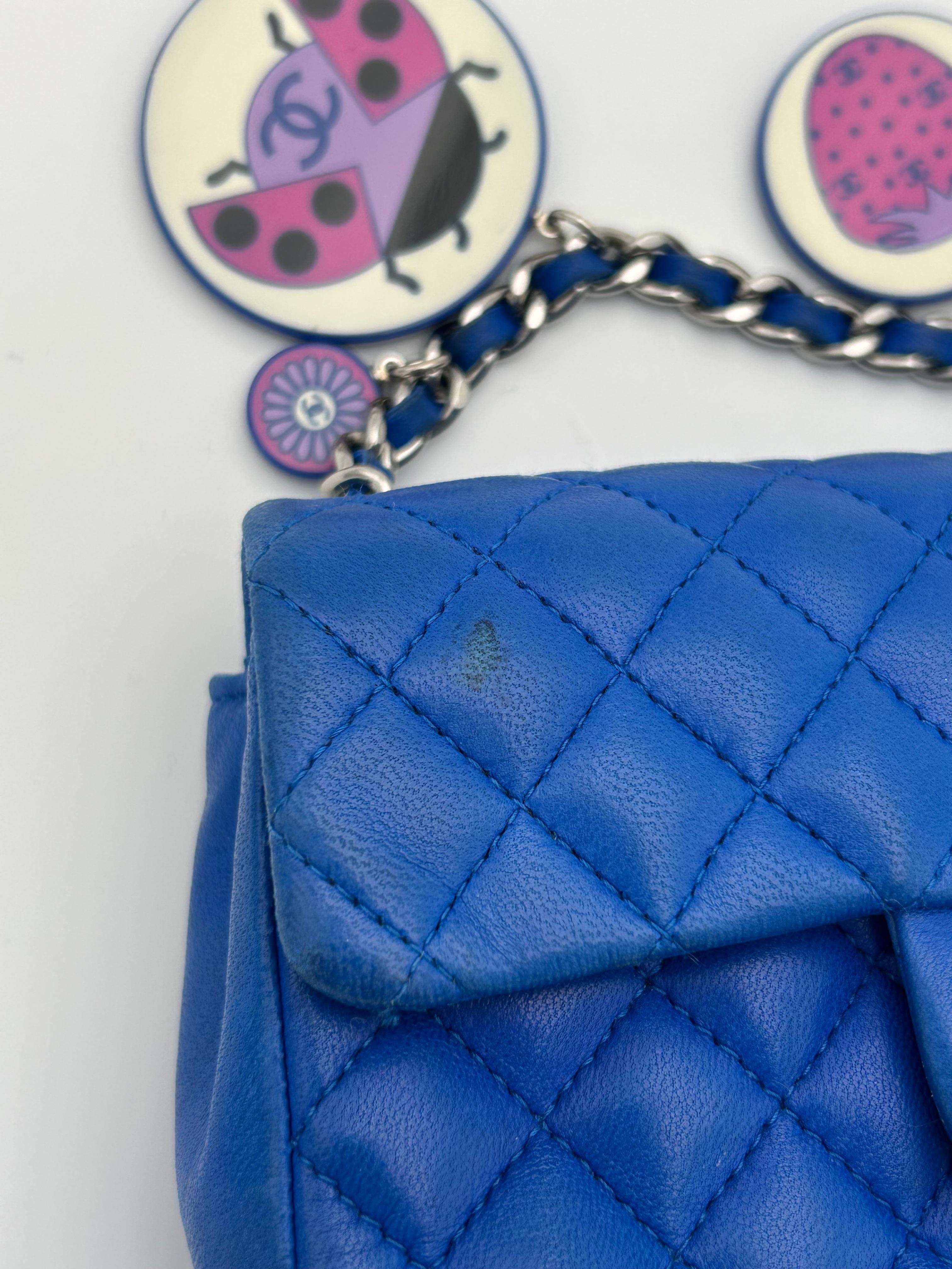 Mini Flap Bag di Chanel in pelle d'agnello trapuntata a rombi, colore blu reale. Questa borsa è dotata della classica chiusura a girello CC con hardware argentato e di una tracolla a catena con filo di cuoio.
  -Due grandi tondi in plastica, uno con