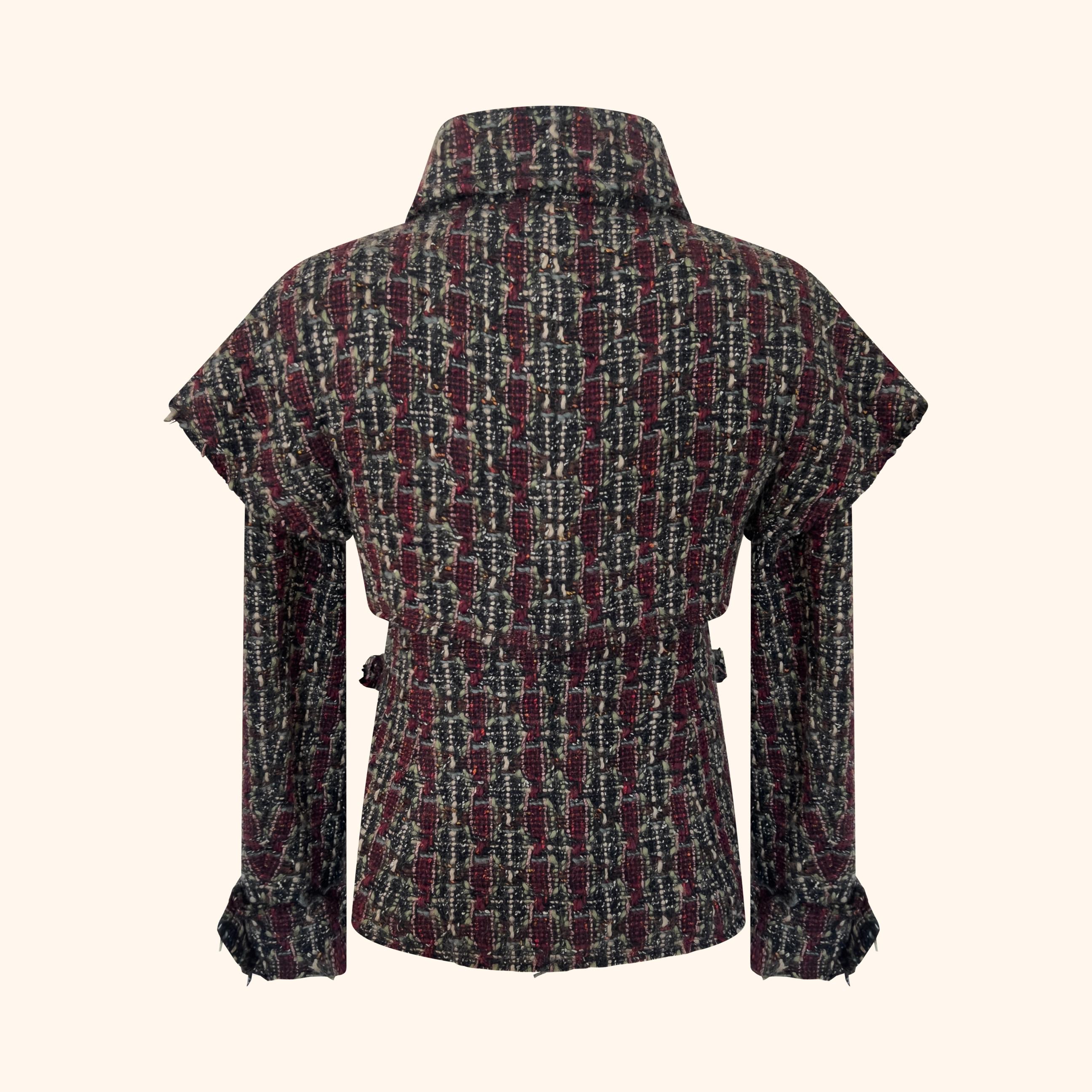 Tweed di lana nei toni del bordeaux, del verde, del nero e dell'avorio, tessuto con filati strutturati per dare profondità e dimensione.
Progettato con un collo alto, spalle scolpite e cintura in vita, crea una silhouette definita.
I bottoni CC