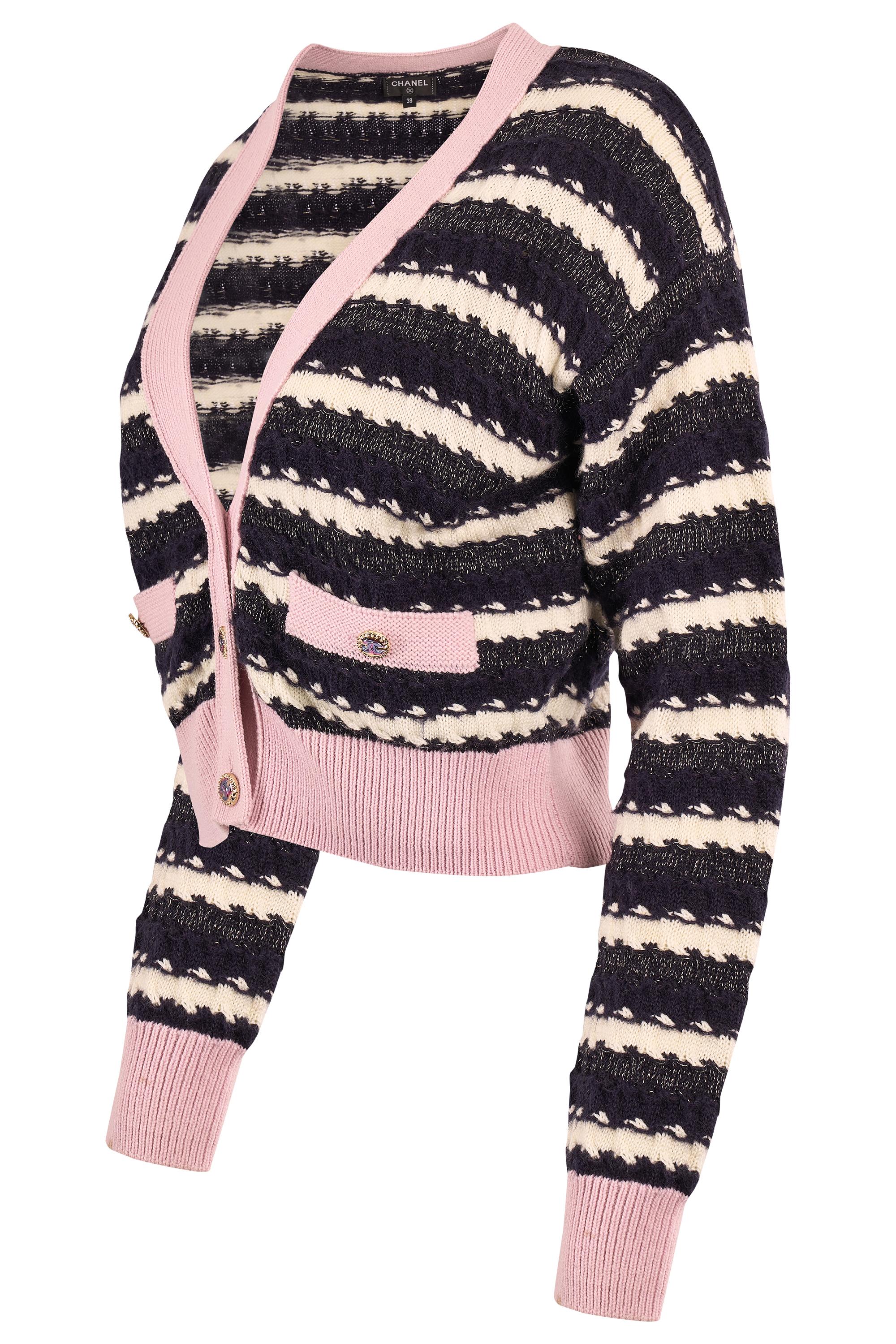 Cardigan Chanel Autunno Inverno 2022 a righe rosa. Presenta una maglia strutturata in stile marinaro  Il modello è caratterizzato da strisce avorio e avorio con sottili accenti metallici per un tocco di lucentezza, mentre le morbide finiture rosa