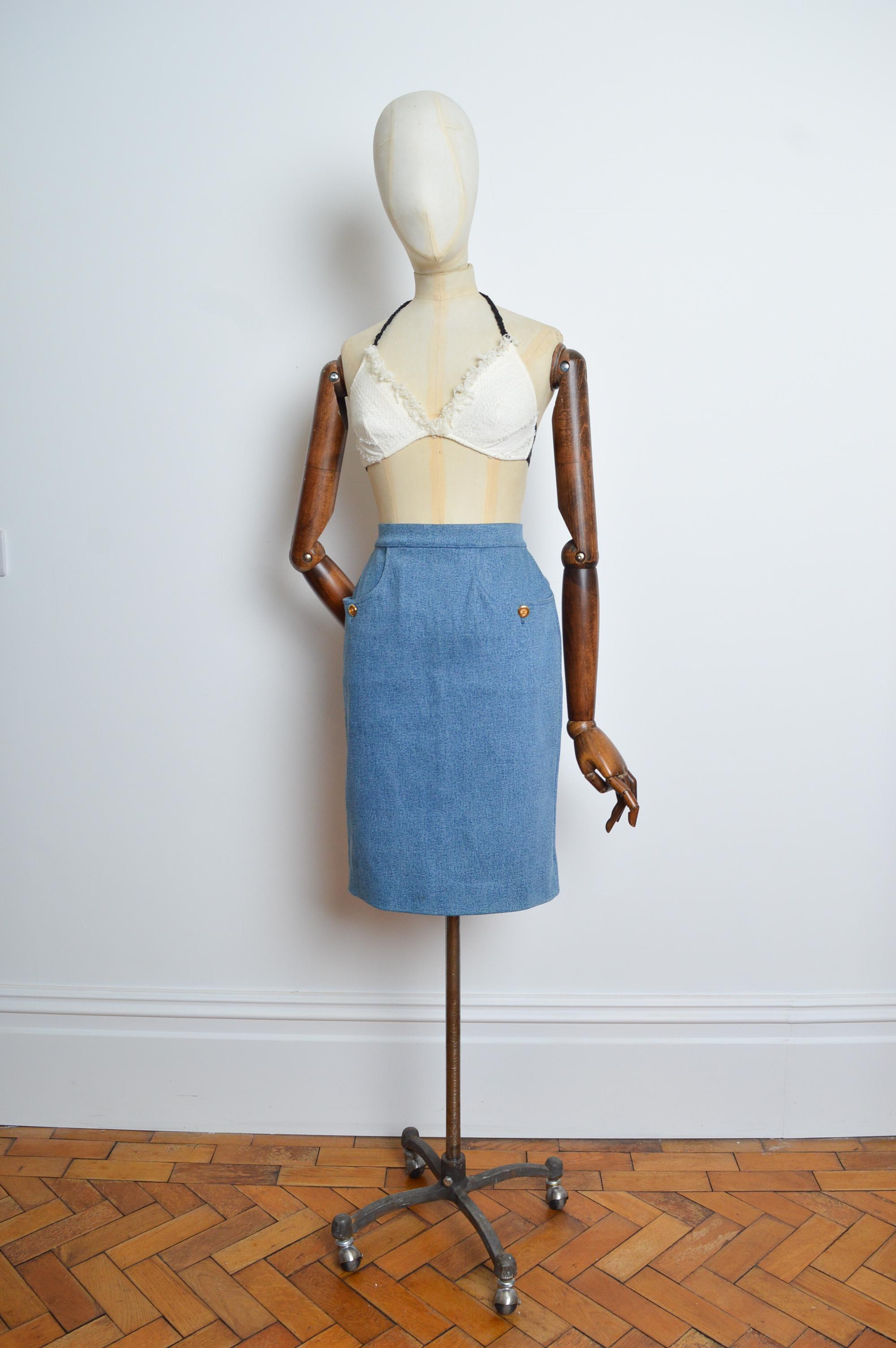 Superb A/W 1991 CHANEL by Karl Lagerfeld mid to light blue denim pencil skirt with Subtle Gold signature button detail. 
Size; 26” Waist 
Measurements are provided in inches (‘’)
Waist; 26 inch waist 
Length; 23 inches. 
Condition; 8/10 fantastic