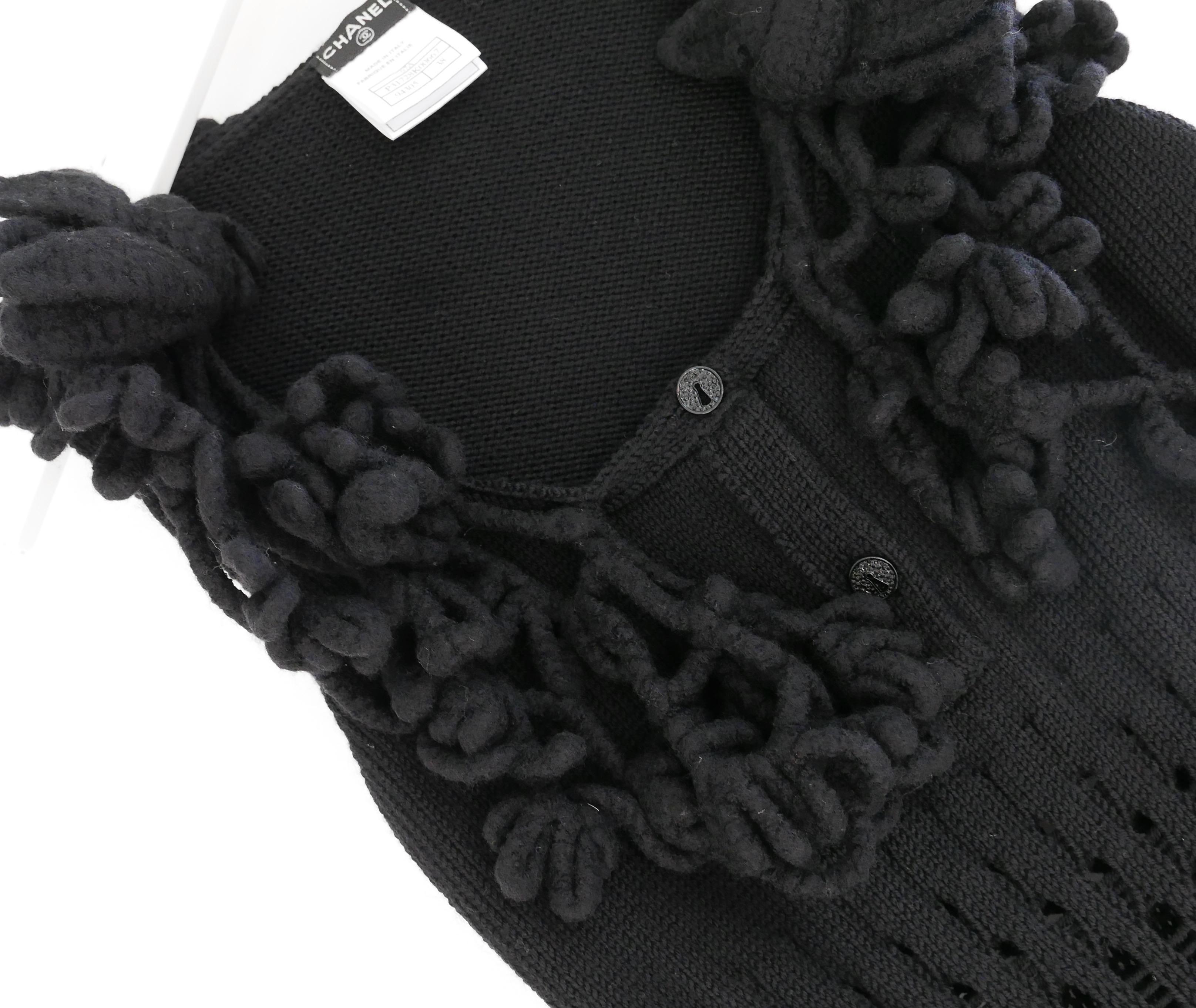 Stunning Chanel sleeveless sweater from the Fall 2007 collection. Unworn. Made from soft black wool and cashmere (70:30) with a fancy ribbed knit, it has sculptural floral wool embellishment to the neck and 2 sparkling lock buttons to the front.