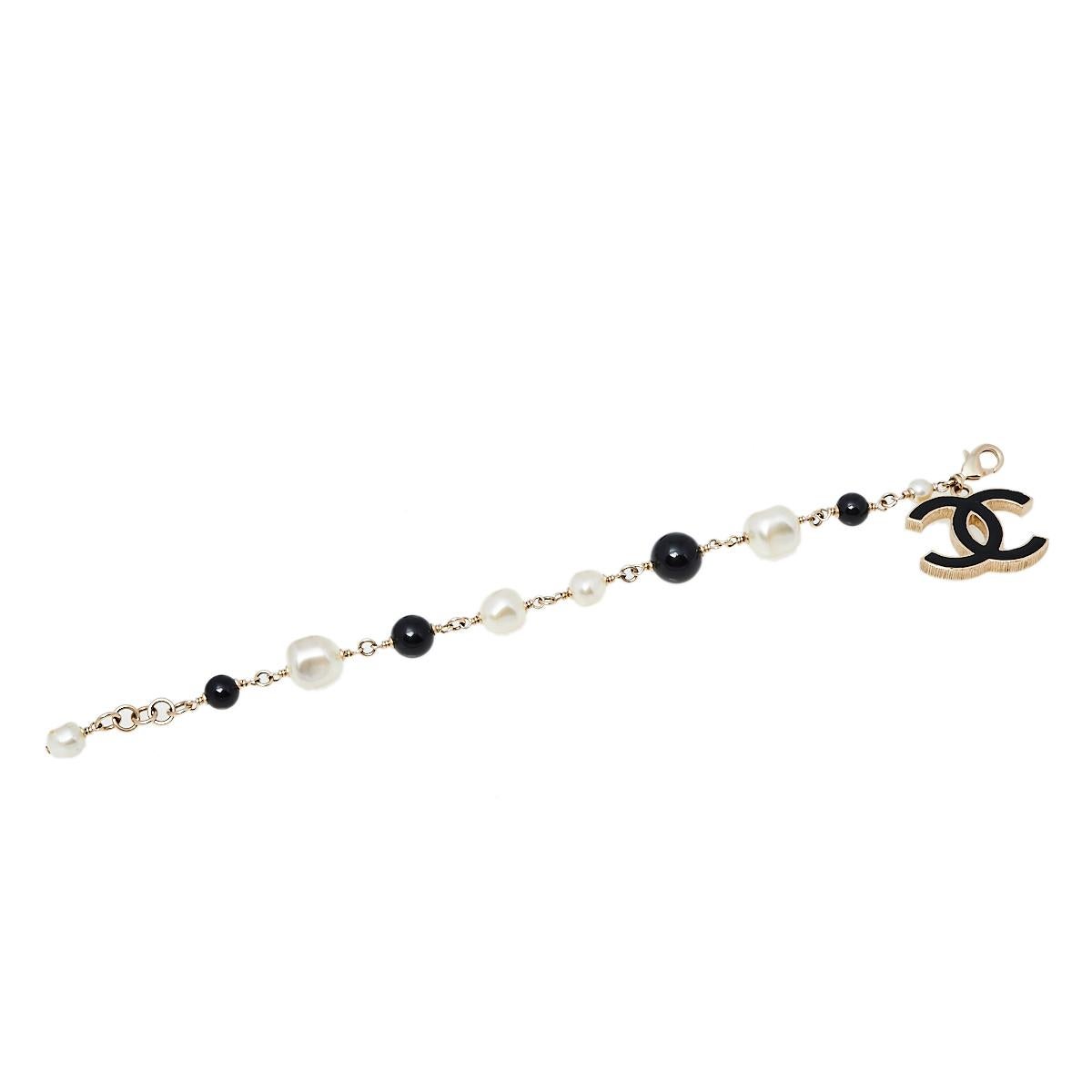 Bound to sit around your wrist and exude beauty, this Chanel piece is a dream buy. It is made from gold-tone metal and on the chain, there are faux pearls, beads, and a dangling CC charm coated with black enamel. The bracelet can be fastened to your