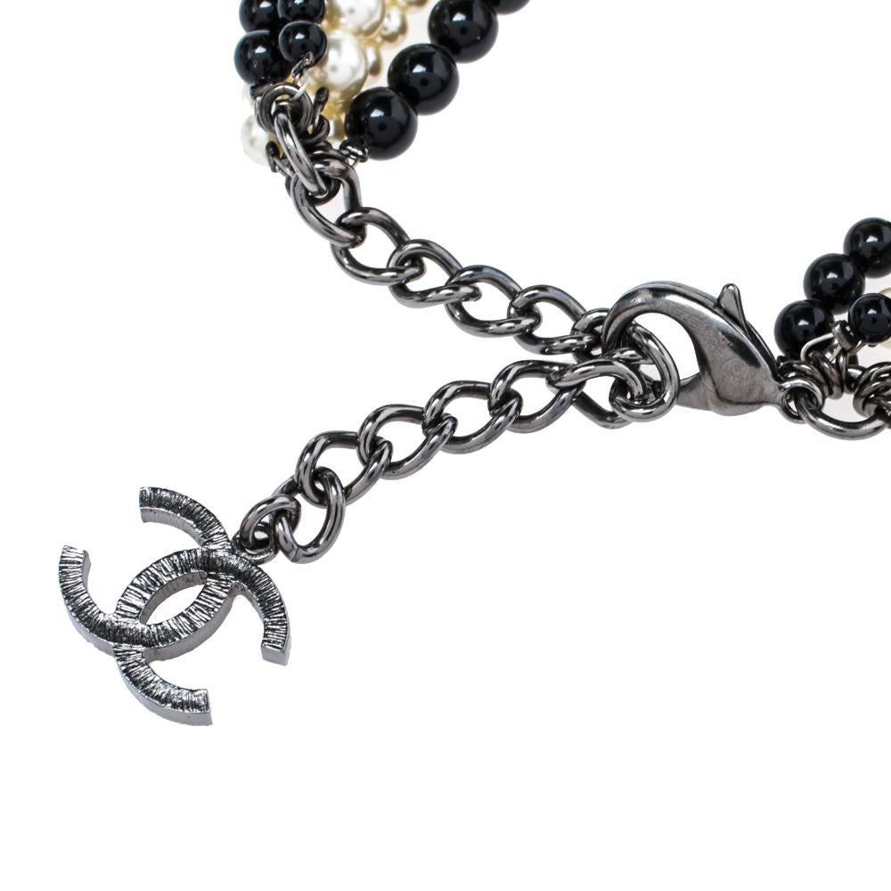 Crafted out of gunmetal-tone metal, this flawless bracelet by Chanel can be your next prized possession. The design involves multiple strands of faux pearls and black beads that will sit around your wrist and fall as tassels. The piece is held by a