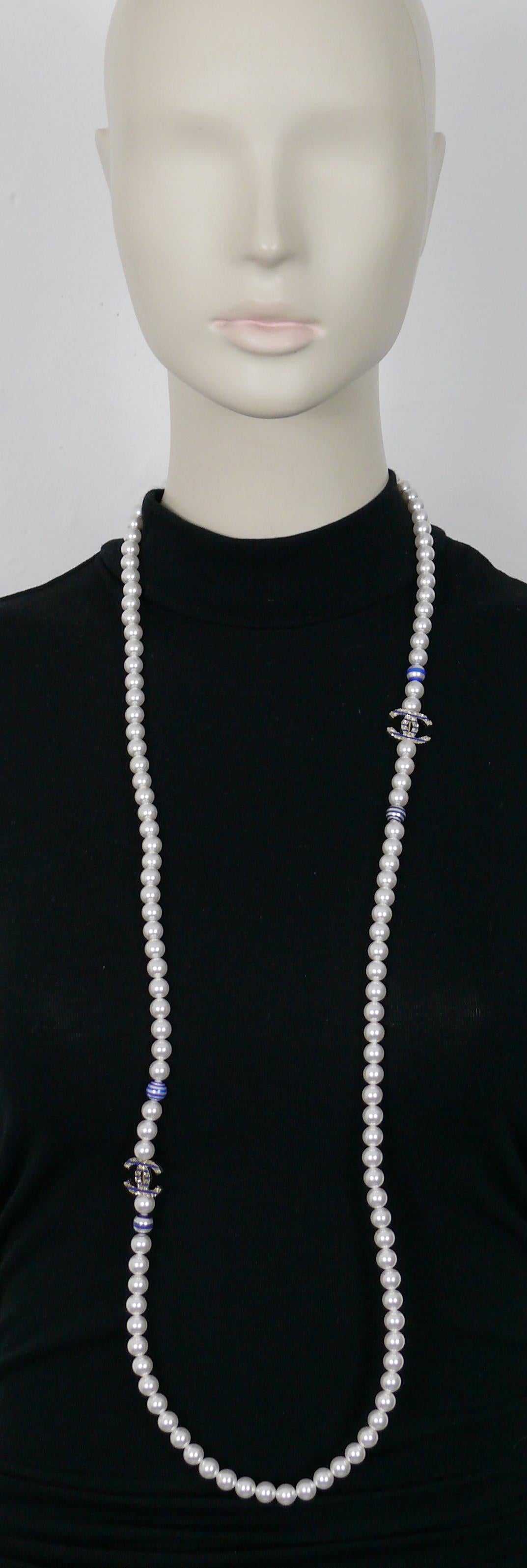 CHANEL Halskette aus weißen Kunstperlen mit vier Perlen und zwei hellen, goldfarbenen CC-Logos, die mit blauen Streifen verziert sind.

CHANEL 2019 Resort Collection (La Pausa).

Verstellbarer Karabiner-Verschluss.
Verlängerungskette.

Laserzeichen