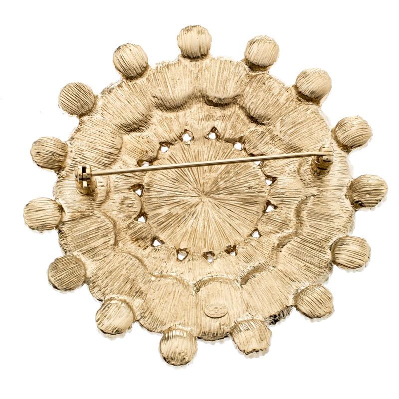 This unique brooch from Chanel is crafted from gold-tone metal into a circular shape. It is gorgeously set with faux pearls all over and carries an embedded eye print at the center, a striking detail which makes this creation adorable and an instant