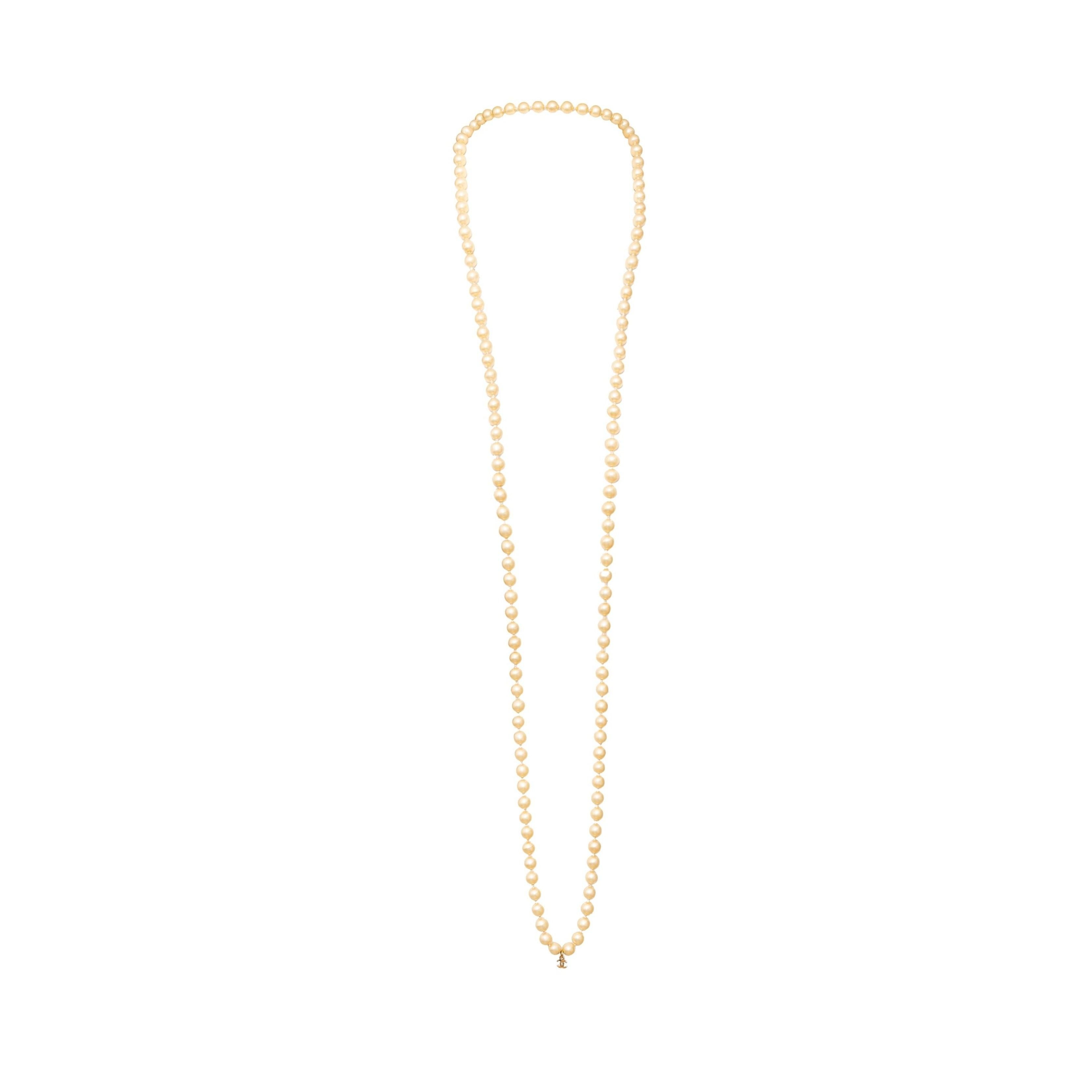 Aggiungi un tocco di eleganza vintage alla tua collezione di gioielli con questa collana di perle finte Chanel degli anni 90. Le perle finte di colore bianco sporco, abbinate al piccolo logo CC, sono una firma sottile ma classica. Avvolgi facilmente