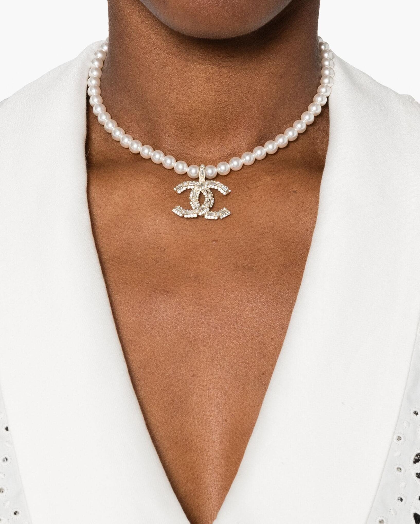 Chanel logo-pendant necklace featuring white/silver-tone
faux-pearl embellishment, crystal embellishment, signature interlocking CC logo, logo pendant, adjustable fit, lobster claw fastening with on a logo plaque. 
Circa 2024 . Made in France
Maxi