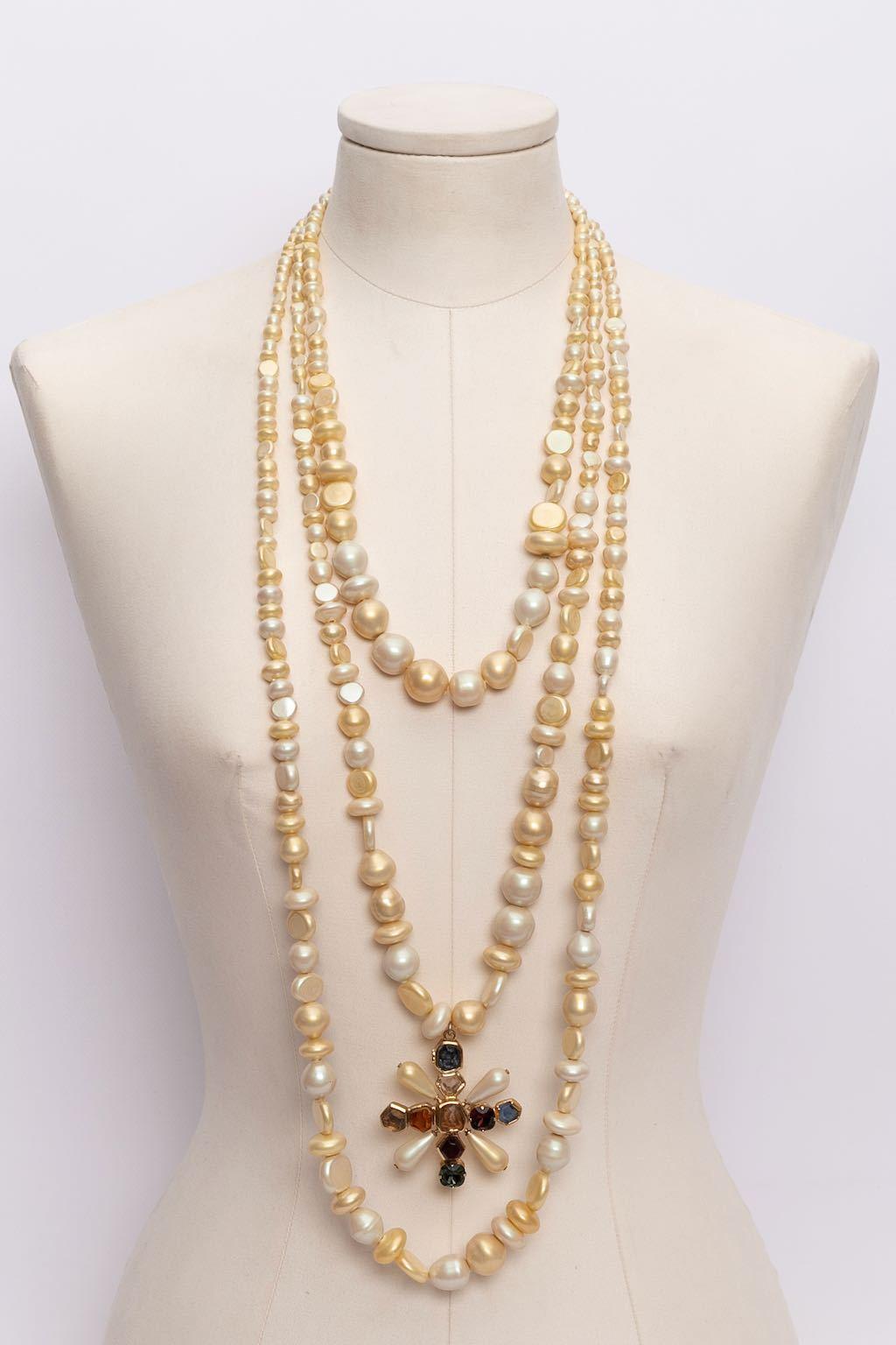 Chanel (Made in France) Necklace made of three rows of baroque faux-pearls hanging a cross-shaped pendant paved with coloured cabochons. Fall-Winter 2001 collection.

Additional information: 
Dimensions: Shorter row length: 64 cm (25.2 in) - Longer