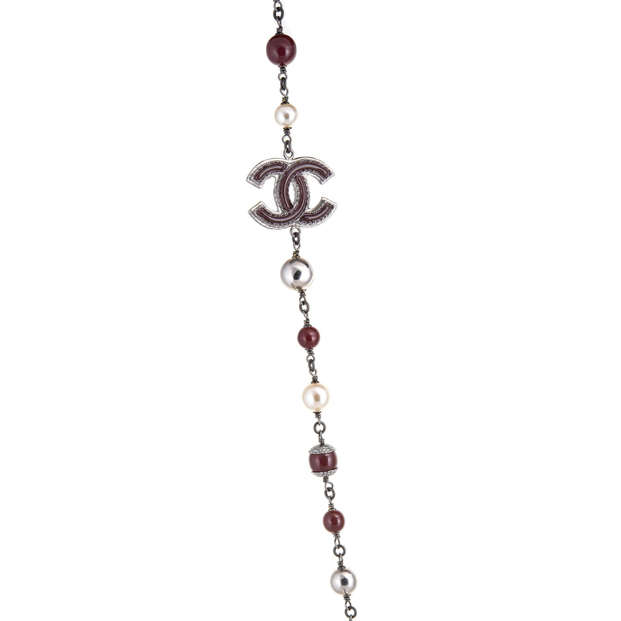 Pre-owned Chanel graduated faux pearl necklace (or belt) crafted in dark silver tone (circa 2014). 

The necklace features graduated 8mm to 12mm faux white pearls, separated with 8mm to 12mm maroon beads. Two CC logos separate the beads. The