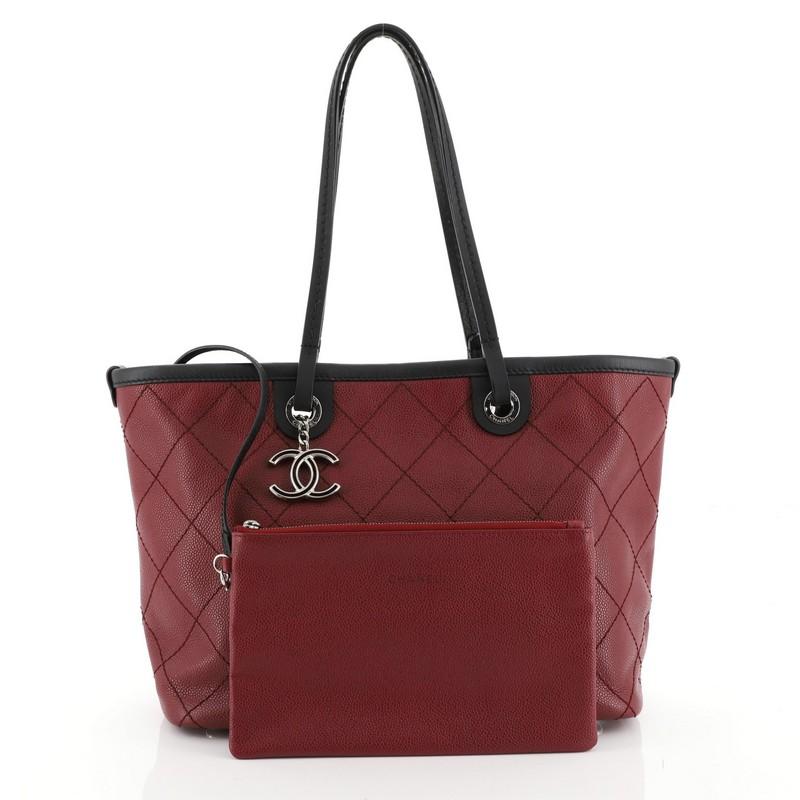 This Chanel Fever Tote Quilted Caviar Small, crafted from red quilted caviar leather, features dual flat leather handles, leather trim, and silver-tone hardware. Its zip closure opens to a black fabric interior with zip and slip pockets. Hologram