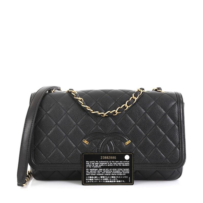 This Chanel Filigree Flap Bag Quilted Caviar Medium, crafted from black quilted caviar leather, features woven-in leather chain strap with leather shoulder pad, large CC logo on the flap and aged gold-tone hardware. Its magnetic snap button closure