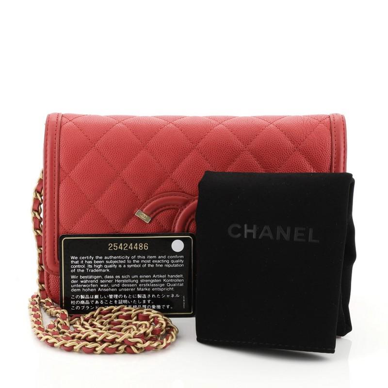 This Chanel Filigree Wallet on Chain Quilted Caviar, crafted in red quilted caviar leather, features woven-in leather chain strap, interlocking CC logo stitched on front and matte gold-tone hardware. Its snap button closure opens to a red fabric and