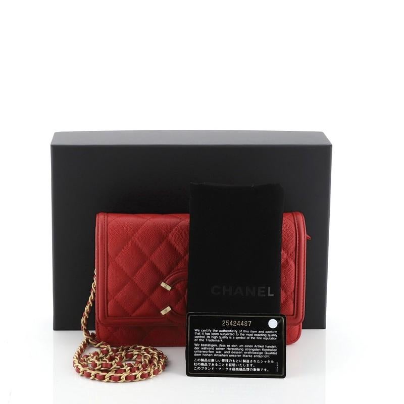 This Chanel Filigree Wallet on Chain Quilted Caviar, crafted in red quilted caviar leather, features woven-in leather chain strap, interlocking CC logo stitched on front and gold-tone hardware. Its snap button closure opens to a red fabric and