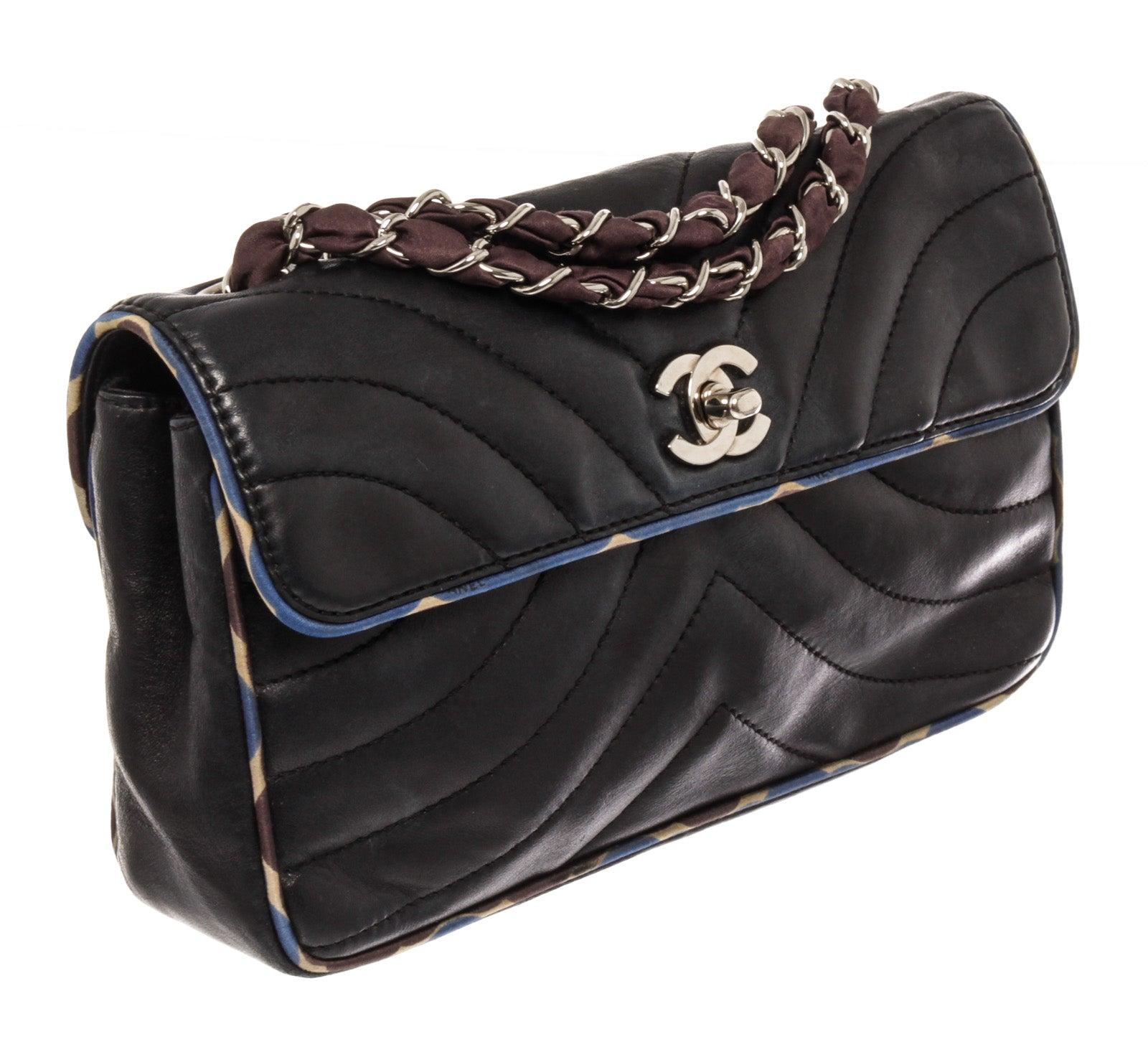 Chanel Flap shoulder bag features black Chevron quilted Lambskin leather with blue silk trim, silver-tone hardware, interlocking CC turn-lock logo at front, entwined silk and chain shoulder strap, front flap that will open to black Jacquard canvas
