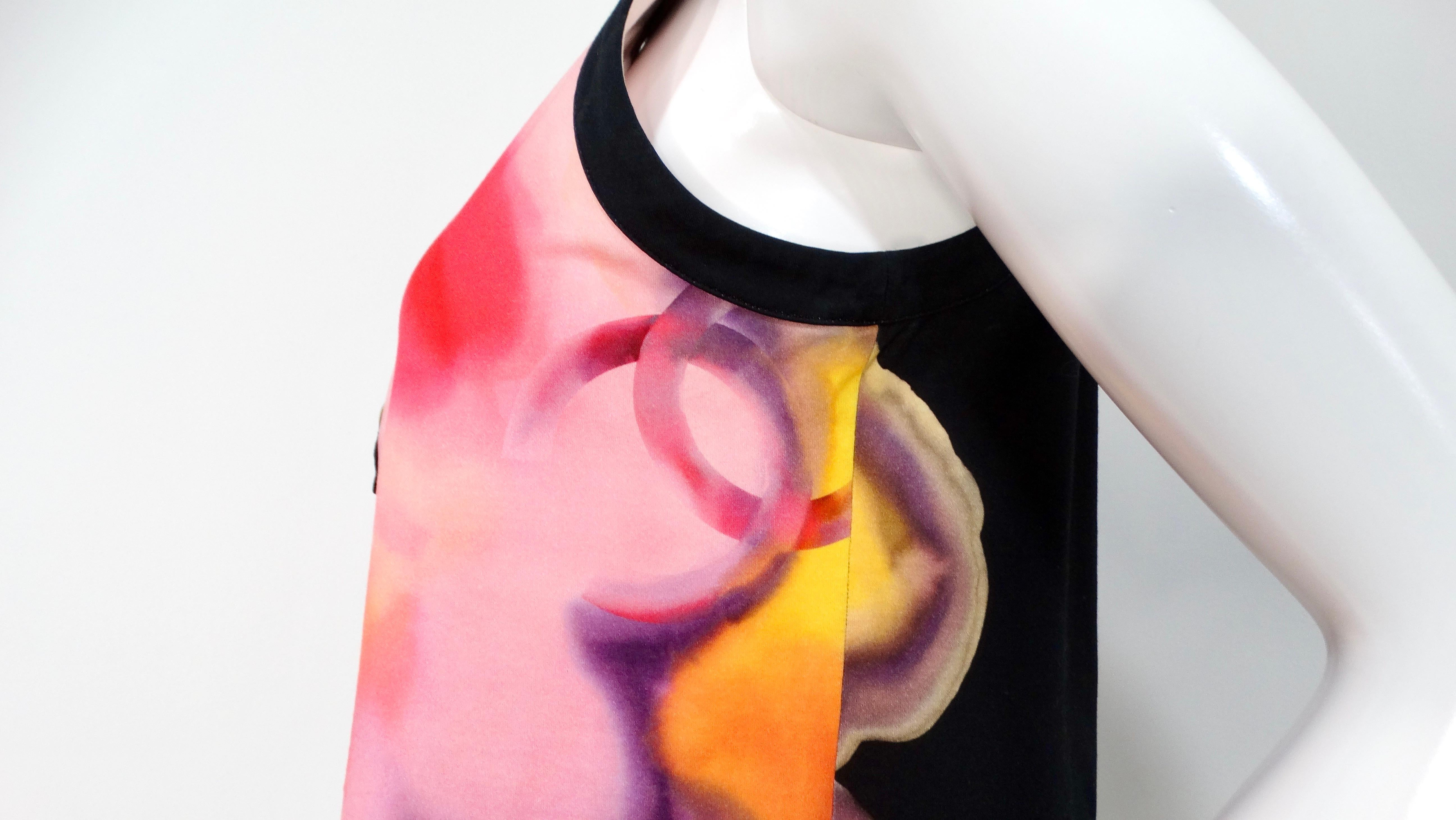 Elevate your wardrobe with the exquisite Chanel Floral CC Print Cotton Sleeveless Button-Down Top. This chic piece features a timeless black base adorned with a vibrant pink and purple floral motif, showcasing the iconic CC logo on the right side