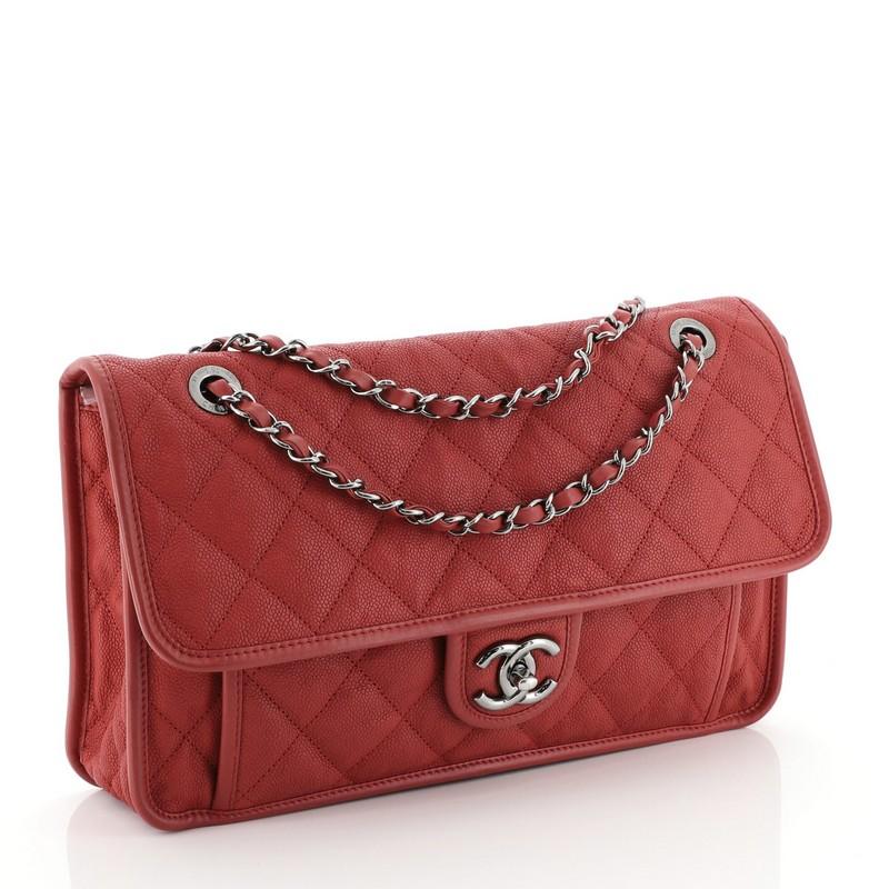 This Chanel French Riviera Flap Bag Quilted Caviar Large, crafted from red quilted caviar leather, features dual woven-in leather chain straps, leather trim, front flat pocket underneath flap, and gunmetal-tone hardware. Its CC turn-lock closure