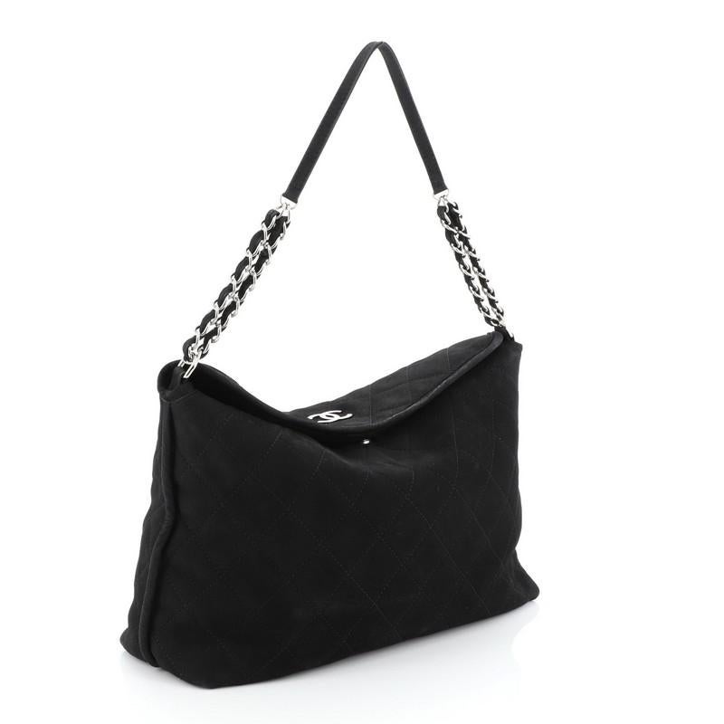 This Chanel French Riviera Hobo Quilted Nubuck Large, crafted in black quilted nubuck, features woven-in nubuck chain link strap and silver-tone hardware. Its magnetic snap closure opens to a black fabric interior with side zip pocket. Hologram