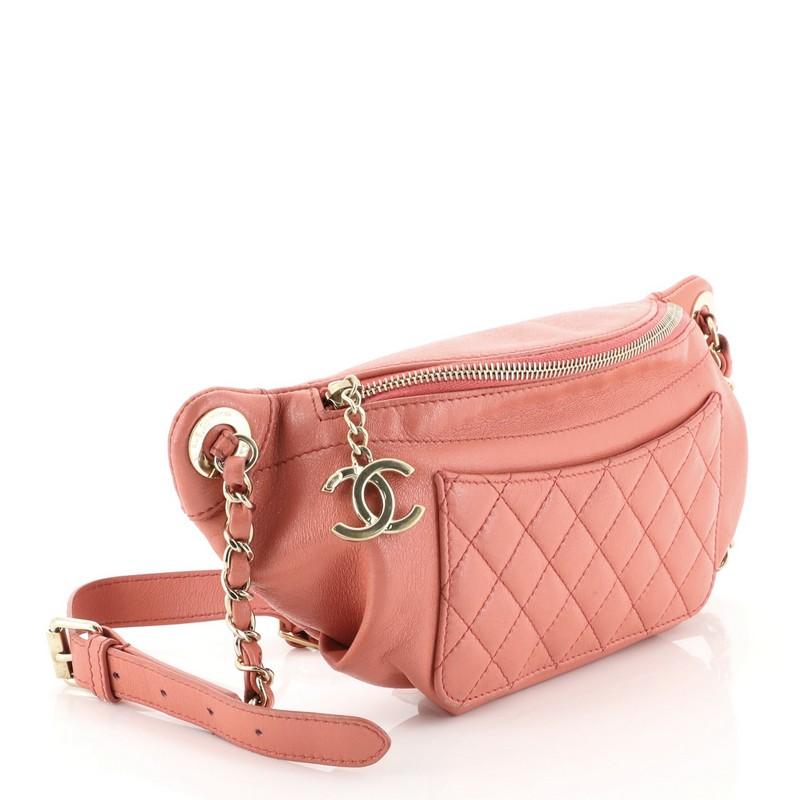 This Chanel Front Pocket Waist Bag Quilted Crumpled Calfskin, crafted in pink quilted crumpled calfskin leather, features woven-in leather chain link and leather waist strap with adjustment links, exterior zip pocket, and gold-tone hardware. Its top