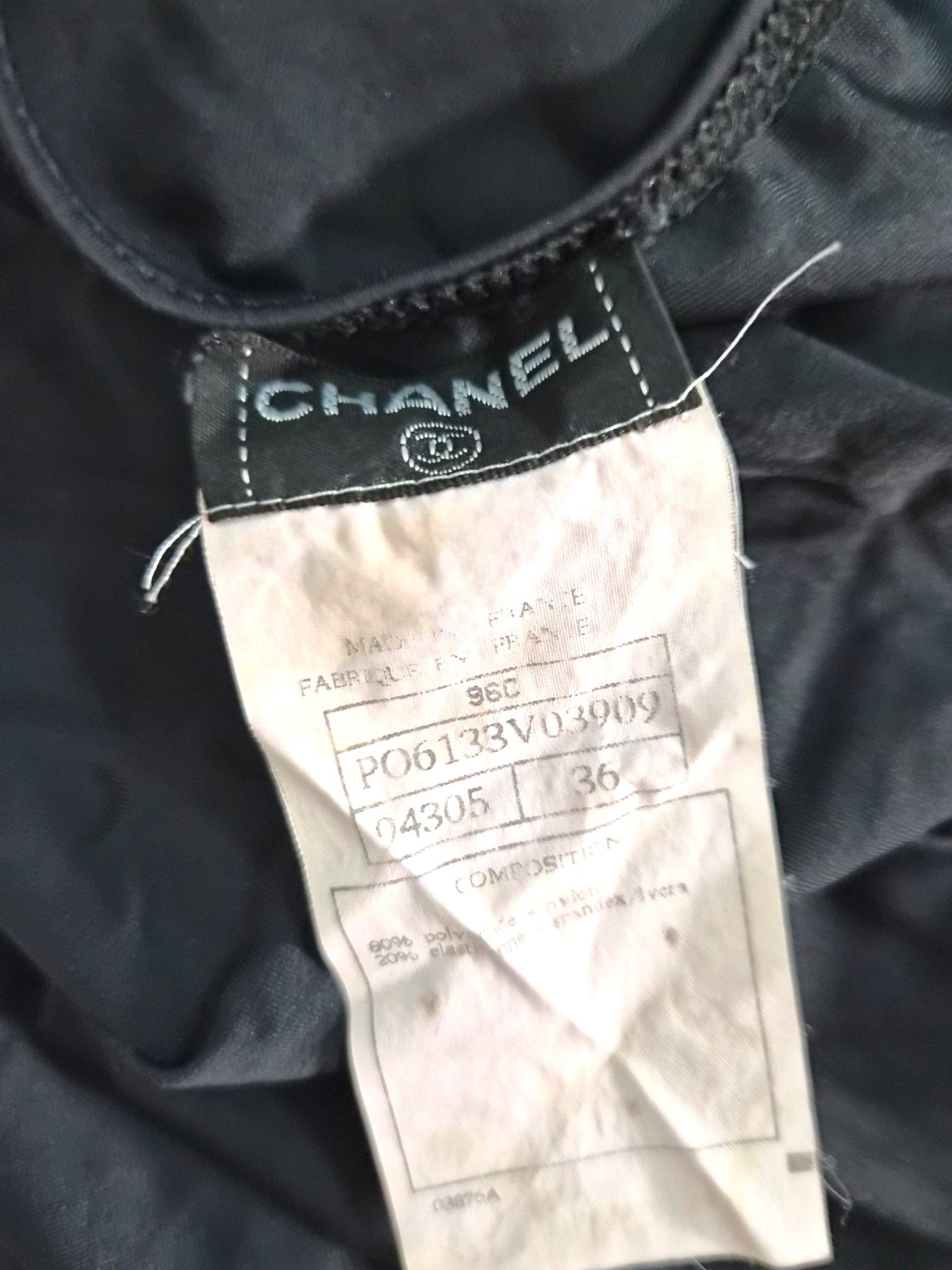 Cette robe midi Chanel de la Collectional 1996 est un exemple élégant du minimalisme raffiné de Karl Lagerfeld. Conçue dans un noir classique, la robe présente un corsage sculpté avec un détail de cravate sur le devant qui forme un nœud doux au