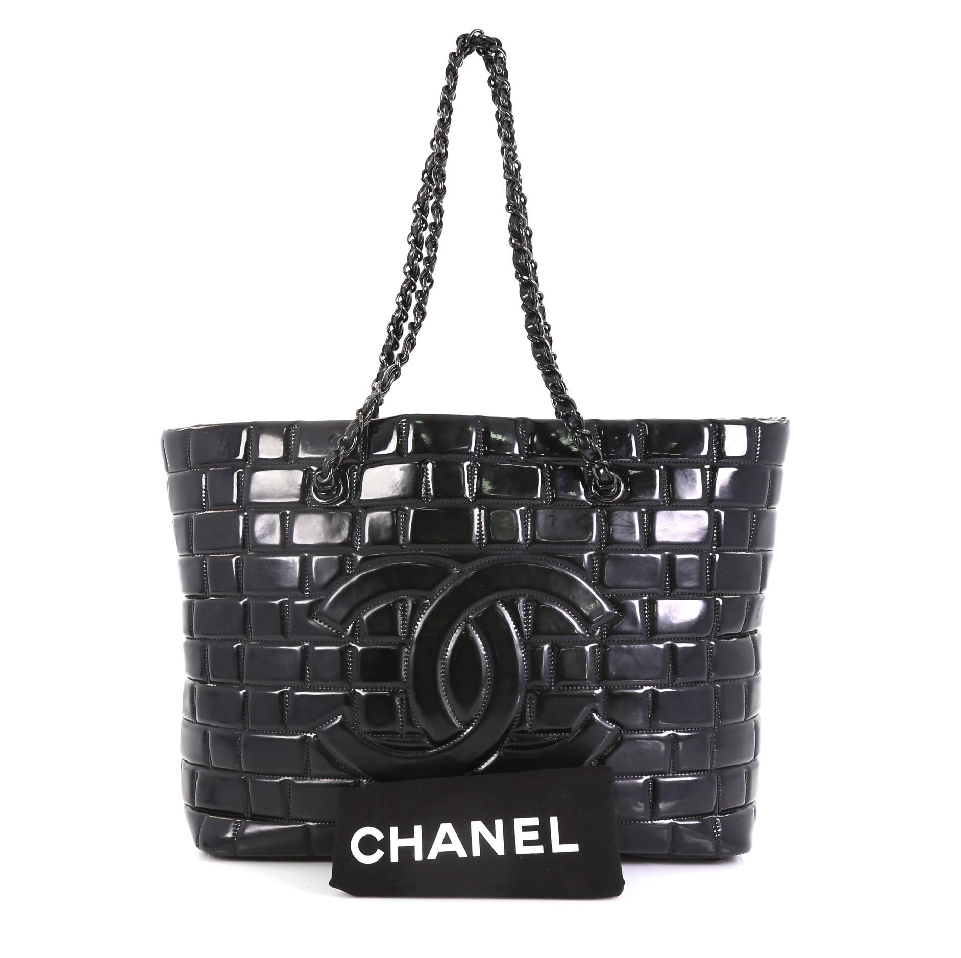 This Chanel Frozen Tote Quilted Vinyl Large, crafted in black quilted vinyl, features dual woven-in-leather chain link straps, CC logo at the front, and black-tone hardware. Its zip closure opens to a black satin interior. Hologram sticker reads:
