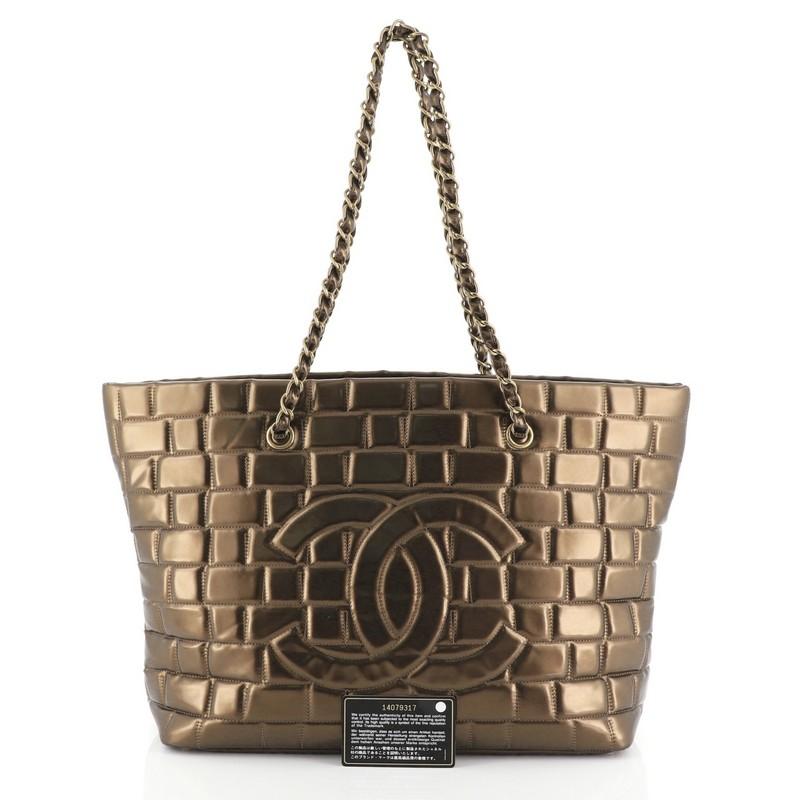 This Chanel Frozen Tote Quilted Vinyl Large, crafted from metallic brown quilted vinyl, features dual woven-in leather chain straps and aged gold-tone hardware. Its zip closure opens to a brown satin interior. Hologram sticker reads: 14079317.