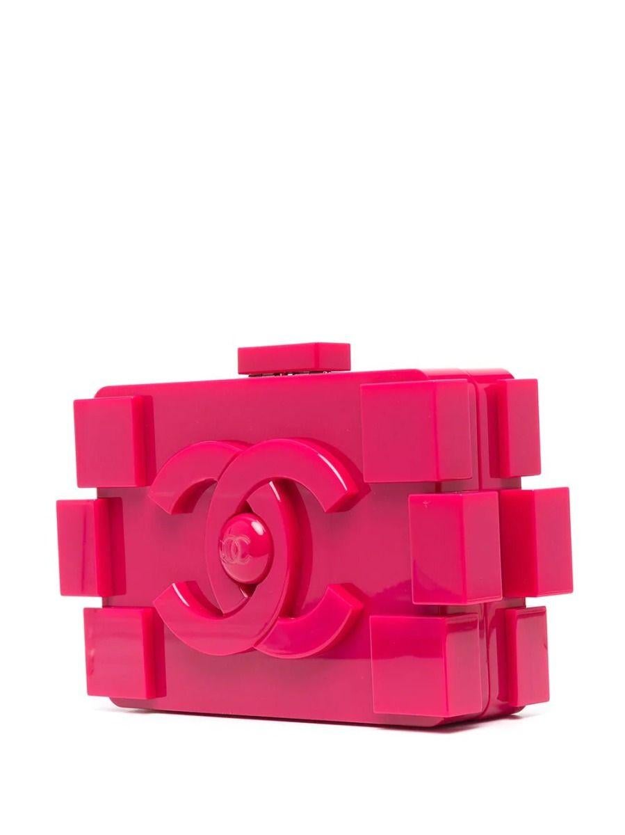 Chanel's playful Lego clutch gets a fierce upgrade. This rare and collectible clutch bag is made of fuchsia plexiglass. Featuring prominent logos across both sides of its hard-case facade and its push closure on top, this piece is a must for any