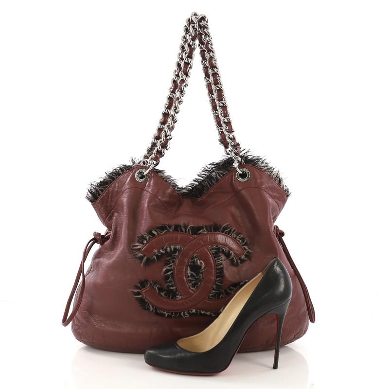 This Chanel Funny Tweed Bon Bon Tote Lambskin Large, crafted in burgundy lambskin, features woven in leather and tweed chain link strap, stitched CC logo with tweed detailing and silver-tone hardware. It opens to a gray satin interior with zip and