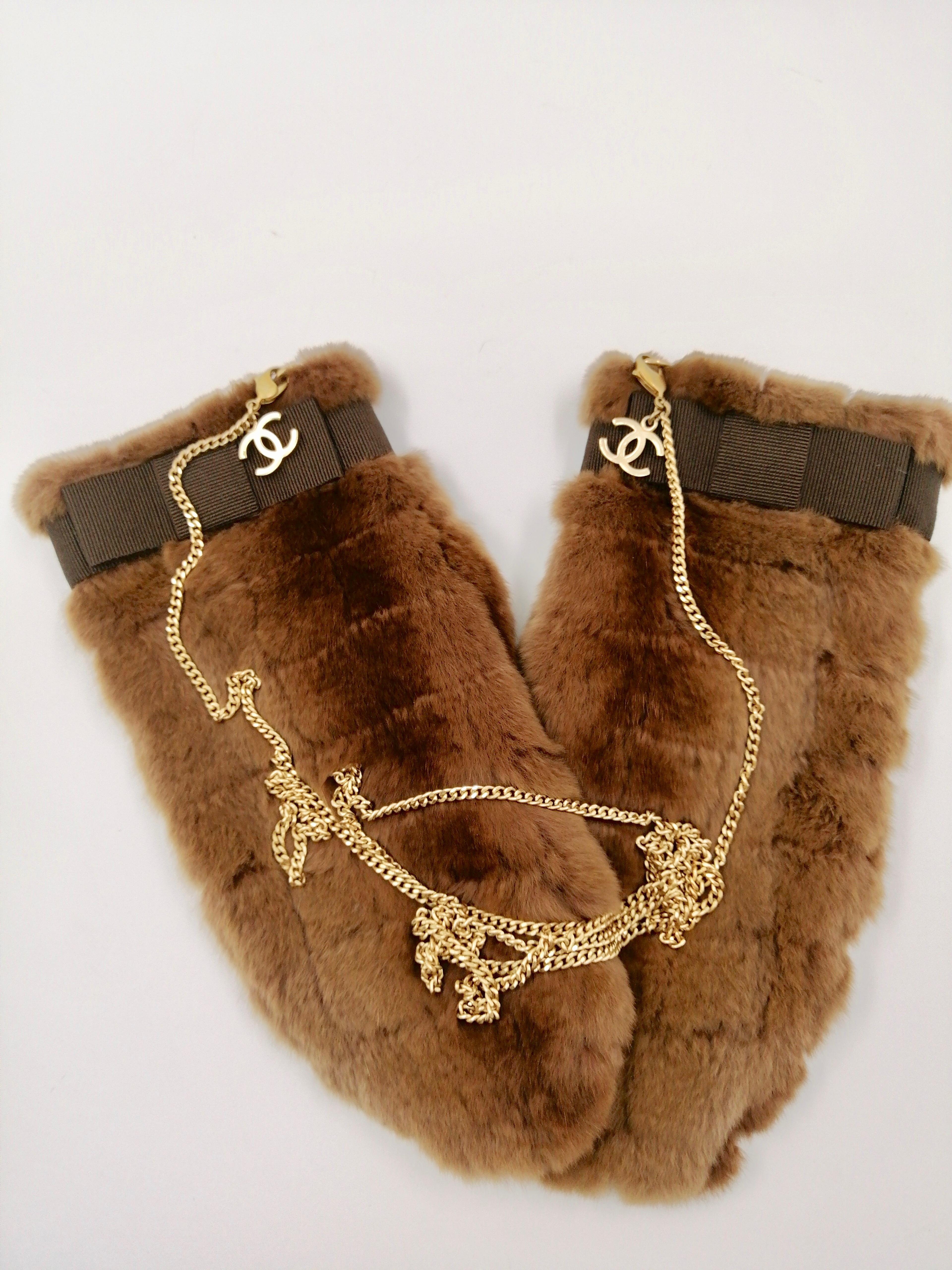 CHANEL fur gloves/mittens
Collection: Fall 2003
Chocolat bar quilted mittens/gloves in honey fur, ton sur ton gros grain ribbons, long golden metal chain.
Size M
Made in Belgium
Composition: 100% vizelle Lining 75% viscose, 25% silk 
Very good
