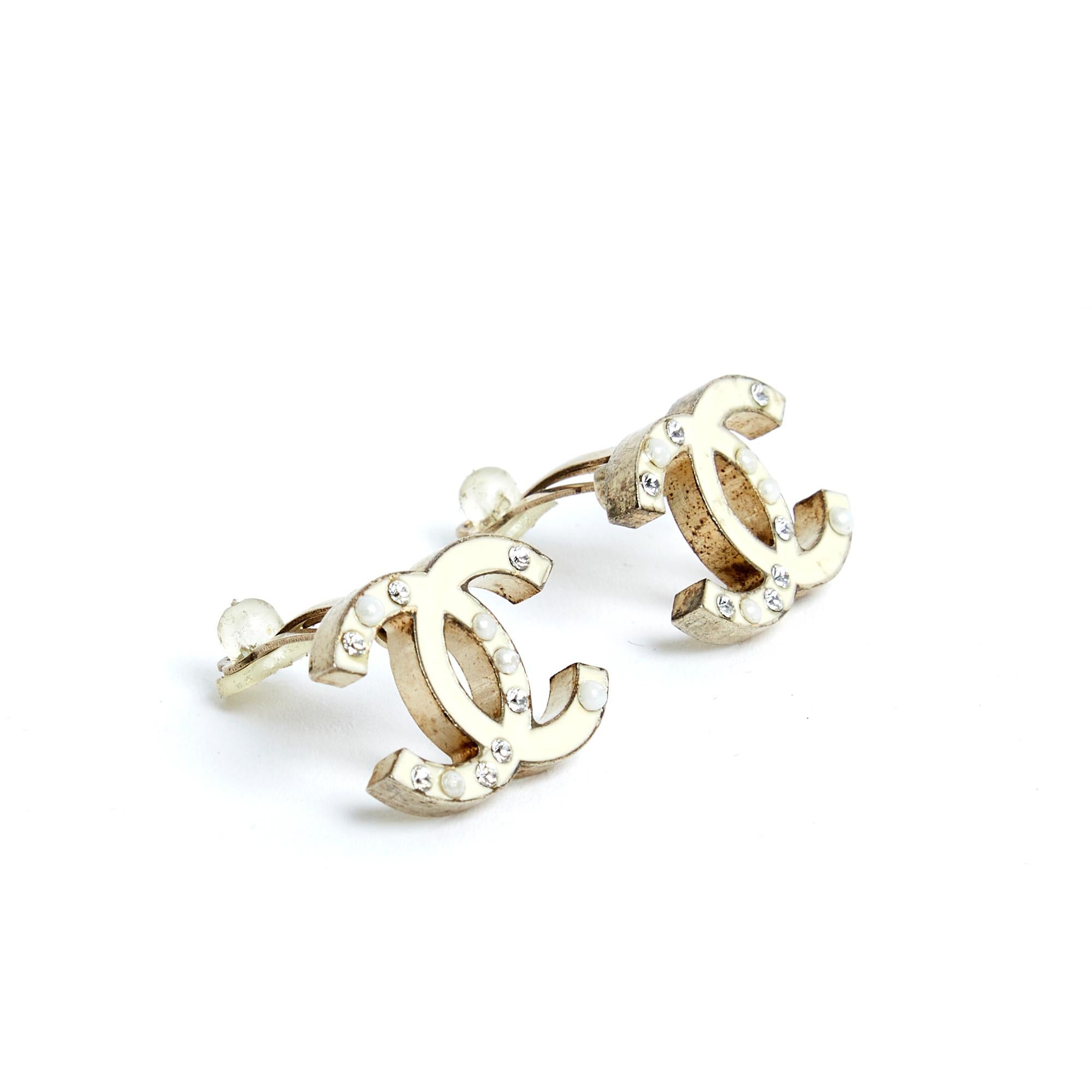 Chanel clip-on earrings in lightly gilded metal (between gold and silver) with a CC logo motif covered in ecru enamel and encrusted with mini white rhinestones and fancy pearls. Width 2.05 cm x height 1.55 cm. The earrings are delivered without