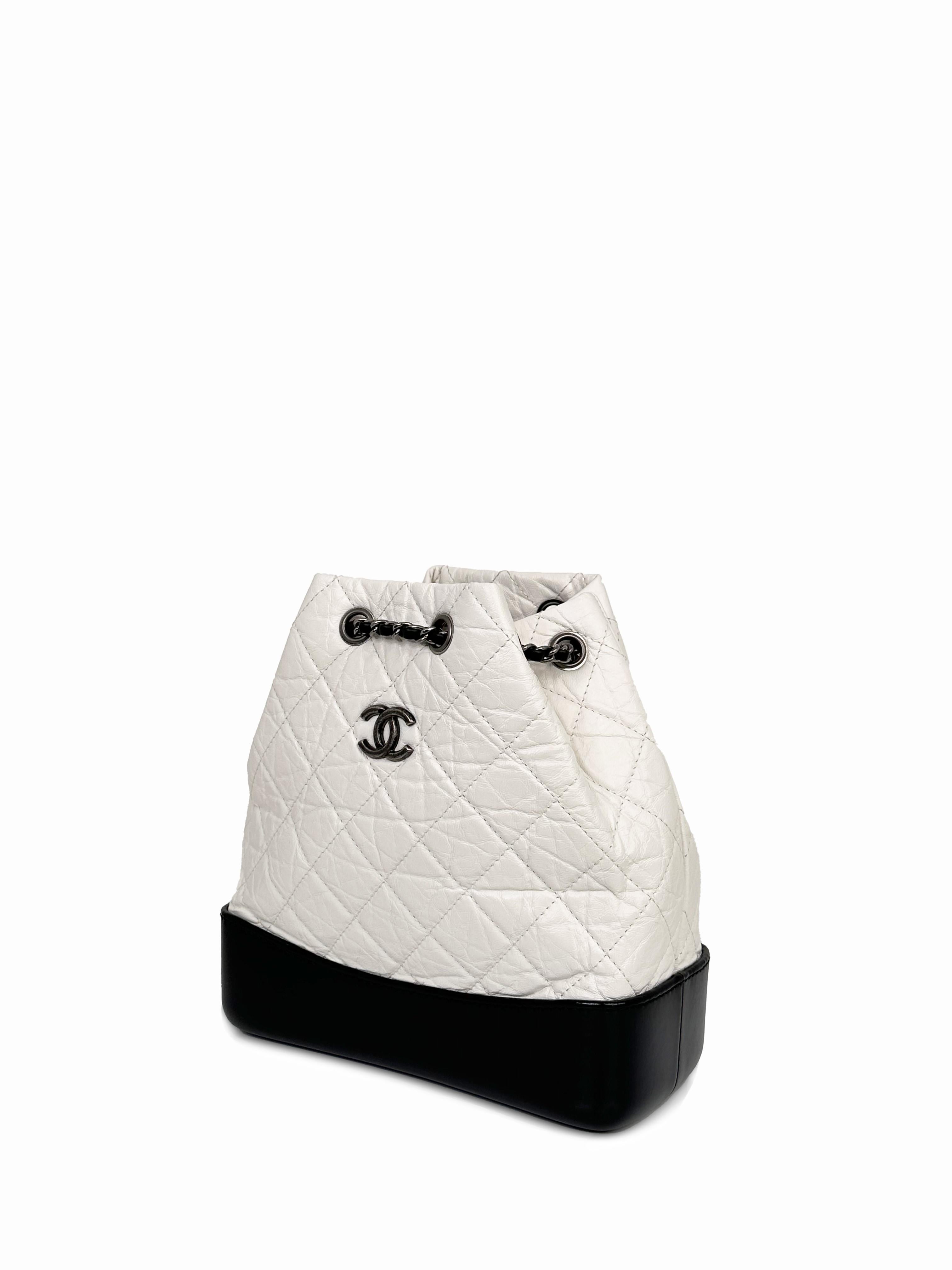 The Chanel Gabrielle Backpack is from a line designed by Karl Lagerfeld for the Spring/Summer 2017 Ready-to-wear show. It features aged white quilted leather, a sturdy base of smooth black leather, the iconic CC logo, and woven chain leather straps.