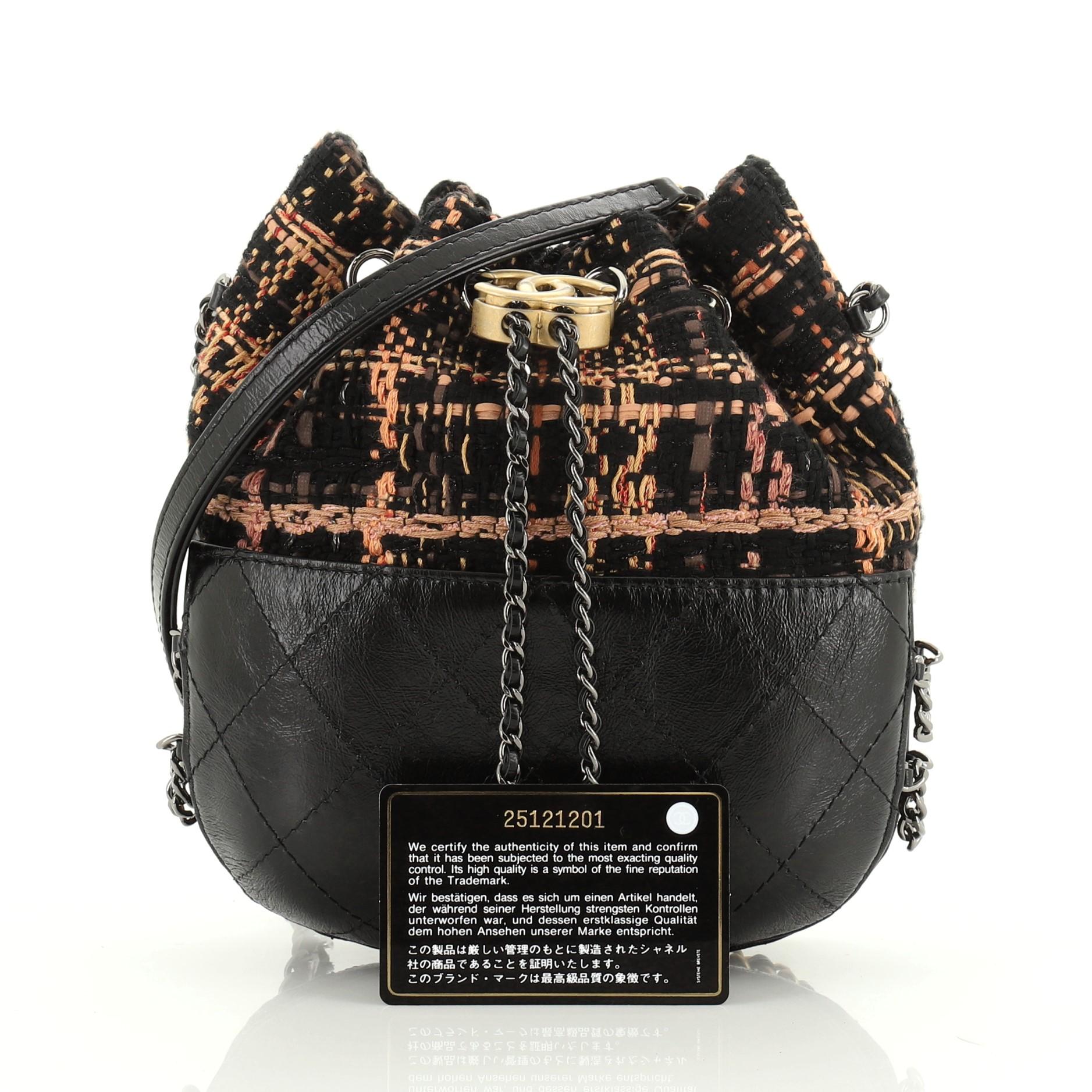 This Chanel Gabrielle Drawstring Bag Quilted Calfskin and Tweed Small, crafted in black, orange and multicolor quilted calfskin and tweed, features woven-in leather chain strap with leather pad, drawstring with CC logo accent, and gunmetal and matte